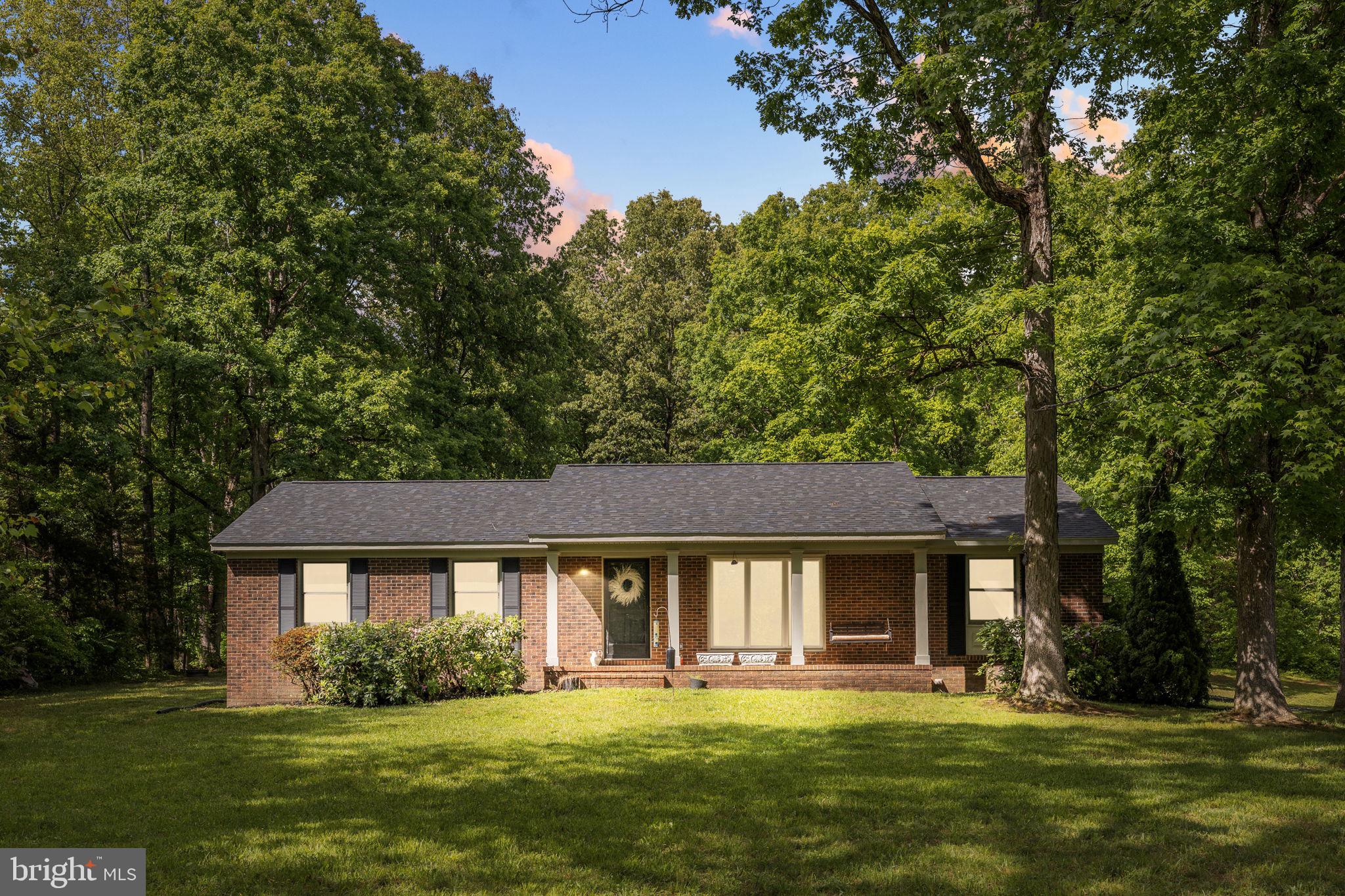 Tucked away on 5.61 acres in the heart of Spotsylvania County, this beautifully designed brick ranch offers the perfect blend of peaceful living + everyday convenience. From the moment you arrive, you’ll feel the lifestyle this property delivers.. quiet mornings, total seclusion, + an ideal location just minutes from everything you need.

Inside, the home has been thoughtfully updated with an open-concept layout designed for both comfortable living + effortless entertaining. The kitchen is truly the heart of the home, featuring granite countertops, a beautiful island, tile backsplash, vent hood, + well-designed finishes that flow seamlessly into the main living spaces. Oversized windows in the living room fill the home with natural light + frame beautiful views of the private front yard + surrounding trees.

The primary suite feels like a private retreat with a spa-inspired walk-in shower complete with dual shower heads. With 3 bedrooms + 2 full bathrooms, this home offers functional space while maintaining a warm + elevated feel throughout.

Step outside + enjoy the beauty of a beautiful 5.61-acre lot,  a true oasis with room to relax, work, + play. The property includes a detached garage/workshop, additional wood shed, + a convenient carport, giving you exceptional storage + utility options for hobbies, equipment, or everyday needs.

Location is everything here. Just minutes from Spotsylvania Courthouse Village, you’ll have quick access to local dining, community events, + one of the area’s most charming gathering spaces, all while enjoying the privacy + serenity of country living. Minimal HOA + a community pond located directly across the street add to the appeal, offering a peaceful setting just steps away without interrupting the seclusion of your own wooded retreat.

A rare opportunity to own a beautifully designed home with acreage, lifestyle, + location all in one... Welcome Home!