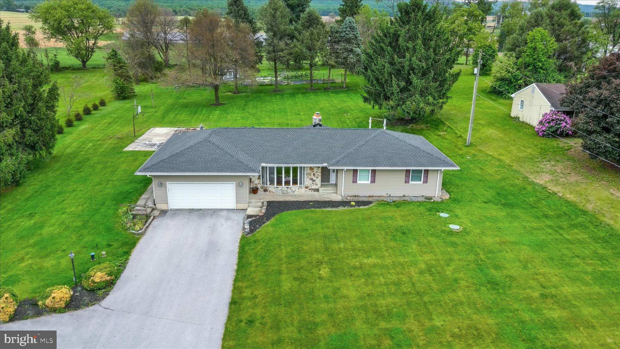 OFFER RECEIVED. ANY AND ALL OFFERS MUST BE RECEIVED BY 5PM  MONDAY JUNE 1st !!!!!!  Located less than 3 miles from the I-81 Newville exit access and sitting back off the Pine Road, what's not to like about this contemporary 1482 sq ft 3BR 2BA, stone and vinyl sided ranch home located on a 1.55 acre rural setting almost halfway between Carlisle and Shippensburg. Liking it starts as you enter the driveway and realize the wide turn around provides convenience to turn around coming out of the garage or park extra cars. The home features a new, less than a year old, shingled roof replacement providing the new owner the comfort of  knowing the interior will be protected. You notice the large bay window in the front looking into  the formal carpeted living room, then as you enter the home you notice the size of the living room from the slate floored foyer. You proceed through the living room to the formal dining room with laminate floors toward the back of the home.  You observe the continuing of the laminate flooring to the left adjoining a wide hall to the vast main floor laundry area which includes a double wash tub sink and ample cabinet storage on the opposite wall and access to the rear patio and deck. Behind those cupboards you notice they conceal the staircase to the basement. The partially finished lower level basement awaits someone to complete the process of entirely finishing the area. With one  exception, the area, a dry cellar with crushed stone flooring, allows storage of canning that has been done. Returning back upstairs to the dining room  through the laundry room, you enter the efficiently designed kitchen with hard counters and stainless steel appliances. The kitchen shares a beautiful vaulted wood and beam ceiling with the family room located on the other side of a dividing wall. The family room includes a stone fireplace with insert. The stone wall reaches from the floor to ceiling. The insert drastically reduces the use of heating oil during the winter months. Three bedrooms, a primary with its own tile floored bathroom with shower, and the other two are all carpeted bedrooms and are of sufficient size.  The hall full bath contains a tub shower combo and is conveniently located for other two bedrooms.  The exterior to the rear of the home includes a wood deck and masonry patio immediately accessible from the home. Further detached from the back left of the patio is a large concrete surface for the enjoyment or recreation  or a court type use or roller blading and perfect for fun and entertainment! . The remaining rear portion  of the 1.55 acre lot includes fenced raised garden beds and a shed for storing the tools for maintaining the gardeners tools and the mowing equipment of the new owner's choosing. This property can last a lifetime for the buyer who loves convenient single floor rural living. If it weren't for the requirements of the new job one of the owner's has accepted, this home would not be on the market.