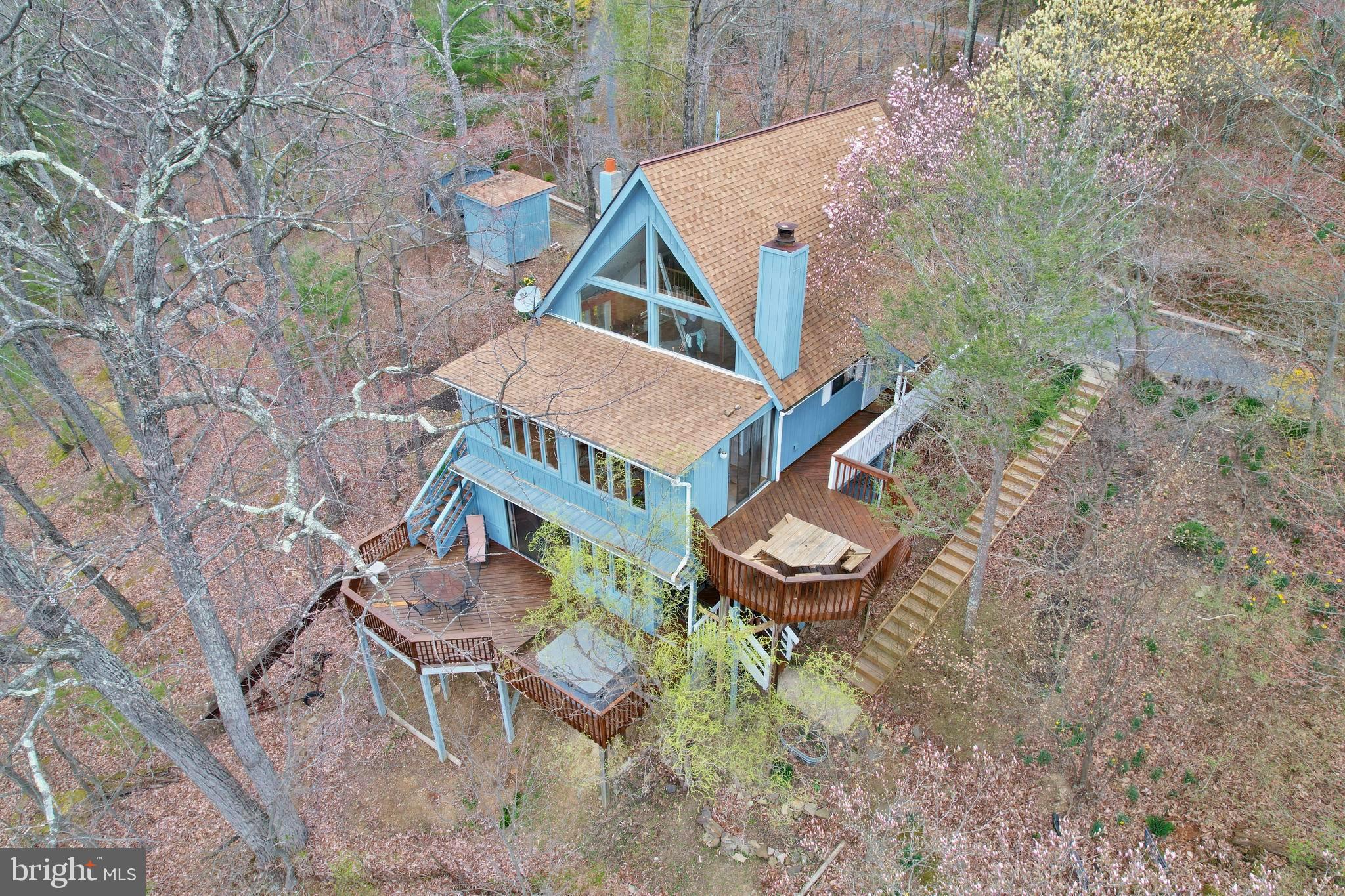 Nestled in a serene and private setting, this charming 1937 sq ft chalet-style home offers breathtaking mountain views from every level. Spanning 2.5 levels and situated on a combined 6.57 acres with an adjacent lot, this property is a true mountain retreat. The top level features a cozy bedroom and full bathroom, a delightful reading nook/loft, and a Juliet balcony perfect for sipping your morning tea. The main level boasts an open-concept design with a beautifully renovated kitchen, new wooden interior doors, a wood fireplace in the living room, and two additional bedrooms with a full bathroom. Enjoy the natural light in the beautiful sunroom or step out onto the expansive decks on the main and lower levels. The spiral staircase leads to a finished basement complete with built-in shelving for a workspace area, a large family/bonus room, a wet bar, and a wood stove. The property also includes a hot tub, two storage sheds, and custom outdoor staircases for easy access to the lower deck. With its well-cared-for home and beautiful natural landscape, this property is just 6 miles from Bryce Resort, making it an ideal mountain getaway. Resort area offers the following: Airport, Library, Dog Park, Indoor Pool, Swimming Pool, Inground Outdoor Swimming Pool, Lazy River, Pickleball, Tennis, Playground, Golf, Mini Golf Lake, Mtn Biking, Skiing, Snowboarding, Ice-Skating Rink, Restaurants to name a few. 1.5 hours from NoVA. -