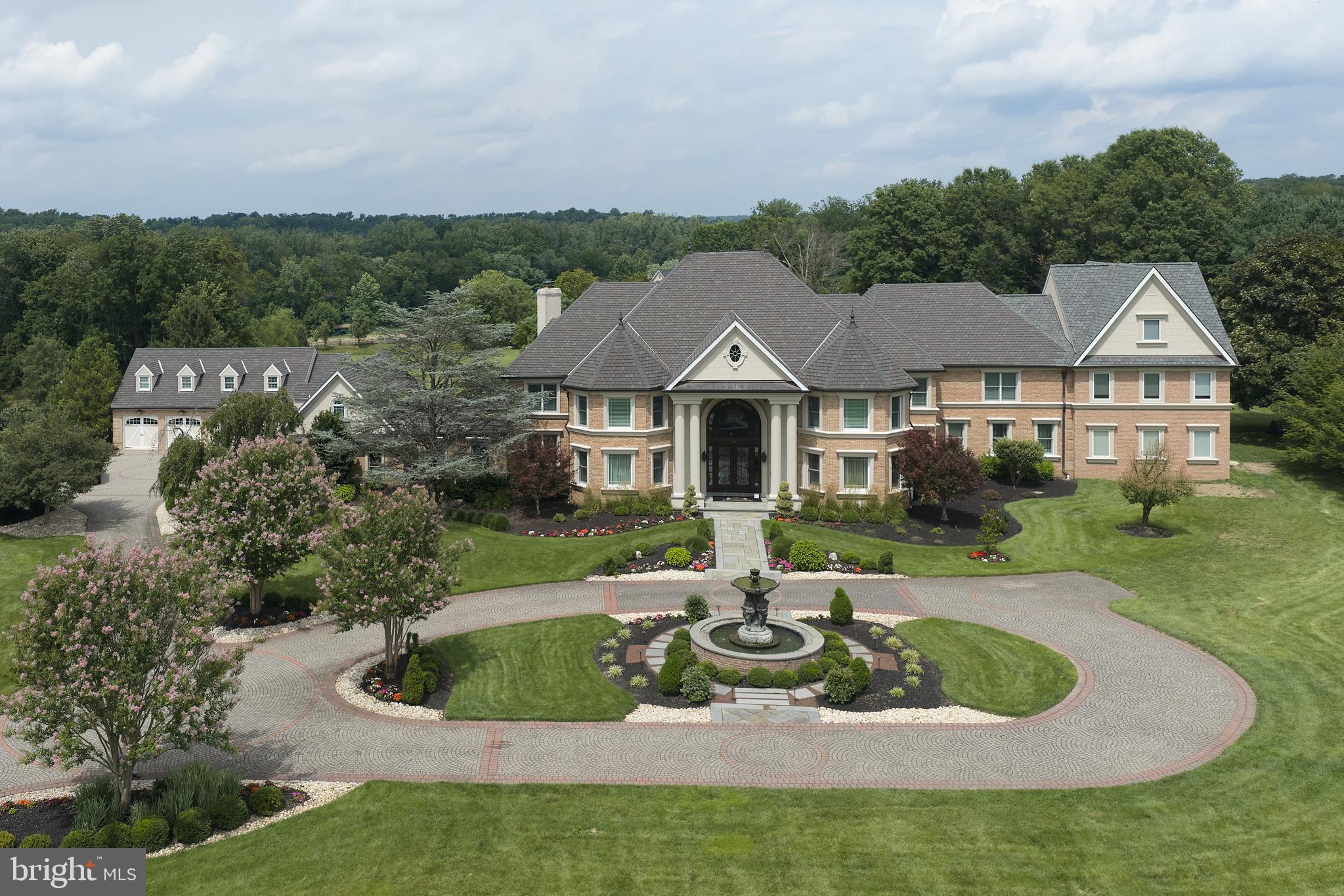 Welcome to Grenoble Manor, an extraordinary gated estate in desirable Northampton Township, located within the award-winning Council Rock School District. Set on 5 private acres, this remarkable 15,246-square-foot residence offers 7 bedrooms, 9 full bathrooms, and 1 half bath, blending timeless elegance with exceptional amenities. A grand circular driveway, elegant fountain, and stately double-door entrance create a breathtaking first impression, while the dramatic marble foyer with dual curved staircases sets the tone for the exquisite craftsmanship found throughout, including hardwood flooring, custom millwork, crown molding, decorative columns, and designer chandeliers. Designed for both luxurious living and entertaining, the home features a spectacular living room with soaring windows, a floor-to-ceiling brick fireplace and built-in bar, an elegant formal dining room with dual chandeliers and fireplace, a private executive office with custom built-ins, and a spacious chef's kitchen with granite countertops, abundant cabinetry, and a large center island. Resort-style amenities include a heated indoor swimming pool with skylights, retractable cover, backyard access, an adjoining sunroom-style sitting area with an electric fireplace, a professional home gym, and a finished lower level complete with a custom stage and private movie theater with recliner seating. The luxurious primary suite offers custom woodwork, a spa-inspired ensuite bath, and an extraordinary three-story walk-in closet, while additional accommodations include ensuite bedrooms, two private apartment suites, a two-story in-law wing, a guest suite with a full kitchen, and additional living space with a kitchenette. Outside, enjoy a private tennis court, outdoor kitchen with built-in grill and island, wood-fired pizza oven, and expansive grounds designed for exceptional privacy and entertaining. Completing this one-of-a-kind estate are a 5-car garage, smart home automation, and a whole-home Sonos surround sound system, creating an unparalleled luxury lifestyle.