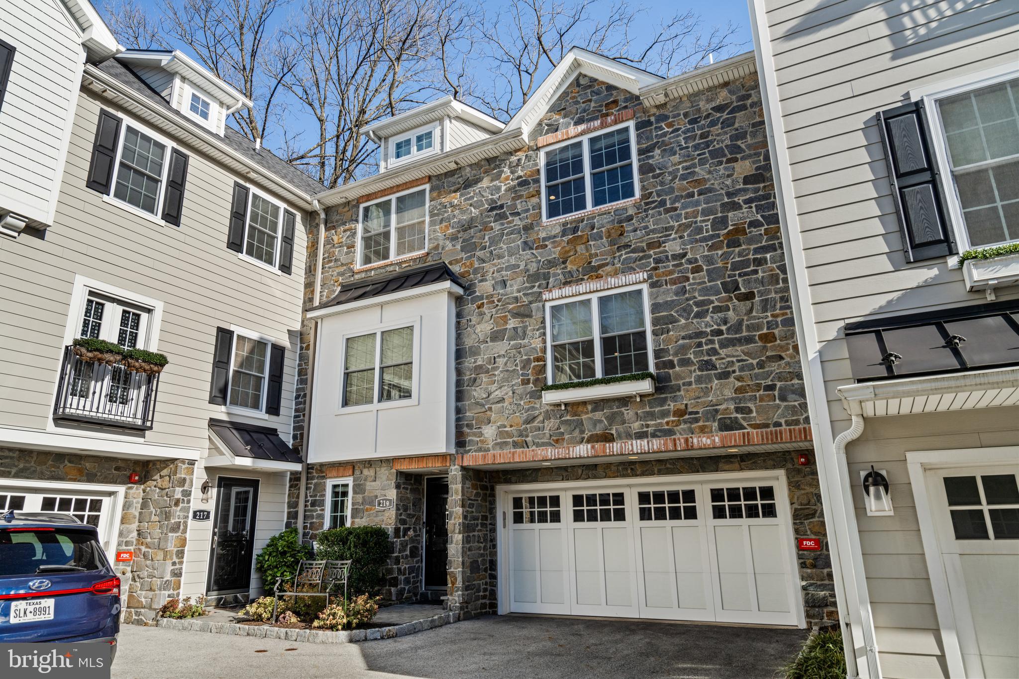 Experience refined, low-maintenance living in this exceptional, elevator-served townhome in the      sought-after Greycott Court community. Perfectly positioned in the heart of Ardmore, this residence offers a rare blend of privacy, thoughtful design, and walkable convenience.
On the entry level, a welcoming foyer introduces direct elevator access, a well-appointed powder room, and a versatile bonus space ideal for a home office, fitness studio, or private lounge. The attached two-car garage is enhanced with an epoxy-coated floor and custom storage, reflecting the home’s attention to detail at every turn.
Thoughtfully upgraded throughout, the home features three spacious bedrooms, three full baths, and two half baths.
The main living level is designed for effortless entertaining and everyday comfort. A beautifully appointed kitchen anchors the space, showcasing a generous center island with bar seating, custom cabinetry, a classic subway tile backsplash, and a suite of high-end appliances, including a GE French door refrigerator, Thermador professional oven with gas cooktop, and a Sharp microwave drawer. Rich wood flooring extends into the dining and living areas, where a gas fireplace, oversized windows, and refined millwork create a warm yet elevated atmosphere. Just off the dining area, sliding glass doors open to a private deck—an ideal setting for al fresco dining or seamless indoor-outdoor entertaining.
Upstairs, the primary suite serves as a serene retreat, featuring a large custom closet and a spa-inspired ensuite bath finished with marble tile and an expansive glass-enclosed shower. A second bedroom is located on this level and is complemented by a full hall bathroom just steps away, as well as a conveniently situated laundry room.
The top floor offers a private upper-level suite with a bedroom and full bathroom, providing a quiet and flexible space well-suited for guests, a home office, or a separate retreat.
Located just moments from Suburban Square, the Ardmore Farmers Market, Lower Merion High School, and regional rail service, this home offers effortless access to Center City Philadelphia while being surrounded by the best of Main Line living, including nearby Wynnewood, Narberth, parks, and trails.