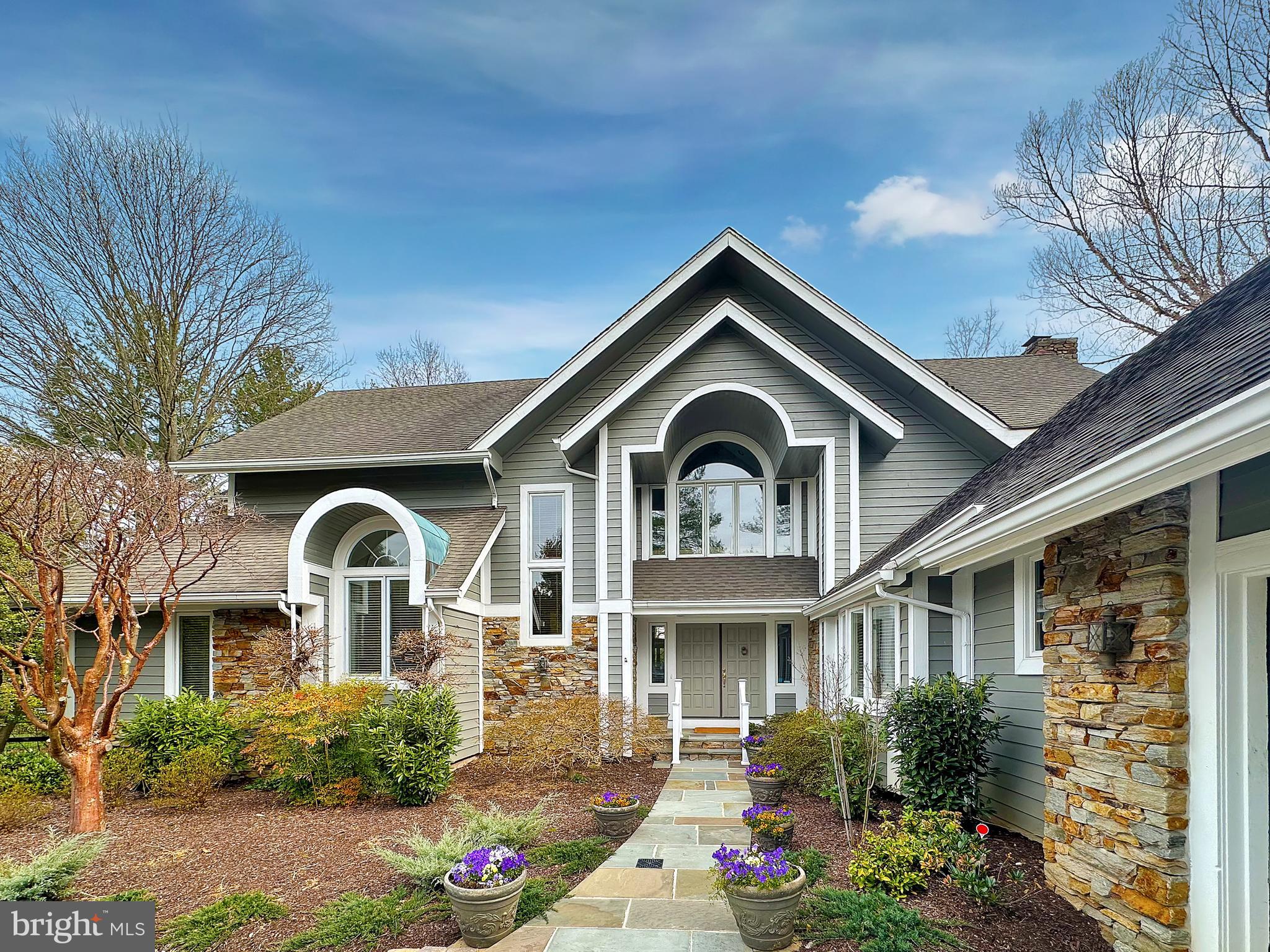 Travel down a shared driveway to this beautiful Ruxton oasis. This spacious stone and cedar contemporary home sits on over .8 of an acre with a private yard and professionally landscaped gardens – providing the perfect “close in” Baltimore County location with easy access to Towson, I-83 and the Baltimore beltway.

1915 Old Court road is a lovingly maintained 5 bedroom, 4.5 home with a floor plan truly made for today’s lifestyles.  Looking for an updated eat-in kitchen with connecting family room?  Check.  Primary bedroom suite on the first floor?  Check.  2 car garage?  Art studio or workshop? Finished basement with a walk out to a flat yard?  Check, check, check!  This one really has it all. 

The main level features expansive cooking and gathering spaces.  You’ll be wowed by the large vaulted living room with wood burning fireplace and beautiful glass-enclosed semi-circular conservatory. Pass through a formal dining room into the large chef’s kitchen that shares a den and sunny breakfast room leading to one of three rear deck and outdoor entertaining areas.  There is also a pantry, powder room and mudroom just off the garage.  At the other end of the main level you will find a primary bedroom suite with two walk-in closets and a large primary bathroom as well as another bedroom (perfect as a guest room, home office or nursery) and full hall bath.

The 2nd level features three nicely proportioned bedrooms and 2 full baths as well as significant storage.  In addition to the almost 3,900 sq feet of above grade living, you’ll also benefit from the lower level featuring another 2,400 sq. feet of finished and unfinished spaces.  The highlight is a large family room/rec room with a second wood burning fireplace, home office space with custom built-ins, and double doors walking out to the beautiful rear yard.  You’ll also find a 40’ brightly lit artists studio/workshop space, laundry room, and storage rooms.

Spend sunny mornings and cool summer evenings under the covered porch or on one of the decks watching children, friends and pets play in the various yard areas. There is a perfect opportunity to add a pool as well.  With so much to offer, you’ll love coming home to your little piece of the world.