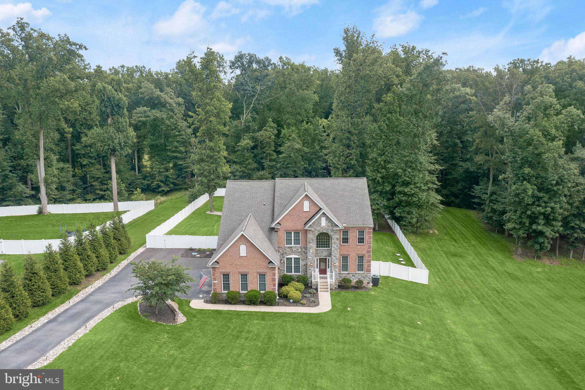 Perfectly positioned on a secluded 1.44-acre lot backing to mature trees, this magnificent Trinity Homes masterpiece in Fulton Manor Valley is the ultimate expression of luxury living. This resort-caliber retreat comes complete with a heated saltwater pool, a fire pit, and storage shed —  all enclosed by a privacy fence and lush treeline. The interior is equally impressive with soaring ceilings, rich hardwood floors, exquisite box mouldings, and an elevated trim package that speak to the home's exceptional craftsmanship. A dramatic two-story foyer with a grand Palladian window welcomes you in, flanked by a formal dining room with tray ceiling, chair rail, and crown moulding, and an equally appointed formal living room. At the heart of the home, a breathtaking two-story family room with a floor-to-ceiling wall of windows and gas fireplace flows seamlessly into the gourmet kitchen, featuring white shaker-style cabinetry, black granite countertops, and stainless steel appliances. The sun-drenched eat-in area opens to a TREX deck overlooking your private backyard oasis A coveted main-level bedroom suite and a spacious mudroom and laundry room complete the main floor. 

Upstairs, a dramatic catwalk landing overlooks the family room below, accessed by both a front and rear staircase. The luxe primary suite offers a tray ceiling, generous sitting room, two walk-in closets, and a spa-inspired bath with a dual-sink vanity, soaking tub, and an oversized dual-head shower. Three additional upper-level bedrooms are thoughtfully appointed — one with a private en-suite, and two connected by a stylish shared buddy bath. The fully finished lower level elevates everyday living with LVP flooring throughout, a sprawling recreation room perfect for a media and game area, and a dedicated home gym with professional rubber flooring. You’ll also find a flex room with sliding door access to the patio and an adjoining full bath, plus a large utility room and separate storage room. Ideally located just minutes from Maple Lawn's vibrant shops and restaurants, yet serenely tucked away — this extraordinary home delivers the rare combination of privacy and prestige.