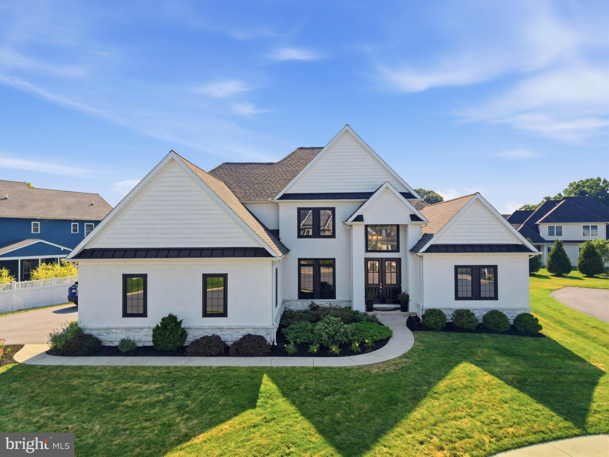 Nestled on a quiet cul-de-sac and situated on a beautifully maintained 0.3-acre lot, this extraordinary 4,900-square-foot livable space home, built in 2018, offers 7 bedrooms, 4.5 bathrooms, and a thoughtfully designed floor plan. Built by Beiler Home Builders, the exceptional craftsmanship is evident from the moment you step through the front door. Elegant architectural details—including wrought iron staircase spindles, classic chair rails, and timeless wainscoting—add warmth and character. While thoughtful conveniences, such as the whole-home central vacuum system, make everyday living feel effortless.
Step through the front entrance into the soaring vaulted foyer. Accented by gleaming hardwood floors that flow throughout the main level, this warm and welcoming space creates an unforgettable first impression. Behind elegant French doors, a beautiful home office features designer lighting and a striking accent wall, creating a peaceful place to work or study. 
The main-floor primary suite is a luxurious retreat, replete with a tray ceiling featuring ambient lighting, an expansive walk-in closet, and a spa-inspired ensuite bath. A contemporary tiled fireplace with a built-in flatscreen TV above creates a warm, calm space for unwinding after a long day. In the ensuite bathroom you'll find a freestanding soaking tub, dual quartz vanity, abundant storage, a breathtaking marble and tile walk-in shower with multiple rainfall showerheads, and a private water closet.
The heart of the home is the spectacular great room, where a dramatic 2-story coffered ceiling, soaring floor-to-ceiling arched windows, and a breathtaking gas fireplace create a space that is both grand and intimate. A wet bar with a built-in refrigerator makes entertaining effortless, while the open layout flows seamlessly into the kitchen and dining area. Home chefs will appreciate the expansive quartz countertops, abundant wood cabinetry, oversized island with farmhouse sink, convenient pot filler by the stove, and generous walk-in pantry. Just beyond, the dining area features built-in bench seating surrounded by sun-filled windows that overlook the stamped concrete patio and open backyard, creating the perfect setting for dinners with loved ones or weekend gatherings.
The remainder of the first floor offers a discreet powder room and a convenient laundry and mudroom with stone tile flooring, built-in cabinetry, and a utility sink. Finally, a second spacious bedroom completes the first floor, featuring oversized windows and a large closet—ideal for guests or a second private office. 
Upstairs, a sitting area welcomes you at the top of the grand staircase, creating a cozy gathering space between three generously sized bedrooms. Each bedroom offers plush carpeting, oversized windows, and walk-in closets. The middle bedroom on that floor, a potential 2nd primary suite, enjoys its own private ensuite bath along with an attached bonus room that could easily become a study, playroom, game room, fitness space, or whatever best fits your lifestyle. An additional full bathroom completes the upper level.
The finished lower level expands the home's remarkable versatility with a spacious family room featuring plush carpeting, an enormous storage room, two additional bedrooms with walk-in closets, and a full bathroom attached to the one bedroom. Whether you're accommodating loved ones, creating guest quarters, or designing the ultimate recreation space, this level offers endless possibilities. 
From its thoughtful floor plan and luxurious finishes to its exceptional flexibility for multigenerational living or entertaining on any scale, this is a home designed to be lived in, loved, and shared for years to come.