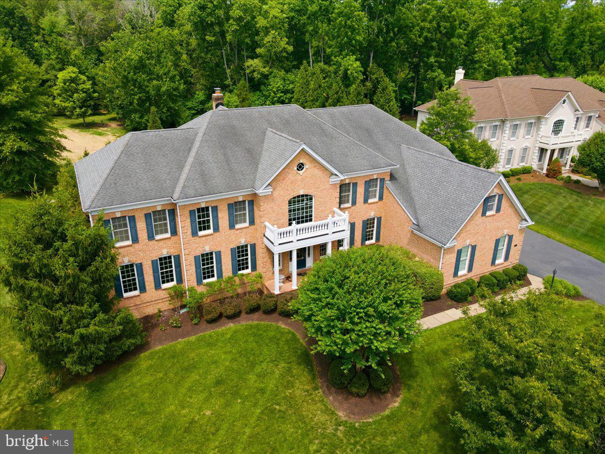 Welcome to 5808 Malvern Hill Court.  This stunning 9,600+ square foot 3 sided brick home offers 4 bedroom suites, 4 full bathrooms, 1 half bathroom, 3 car side-load garage featuring an EV charging station. Situated on a private .69-acre lot backing to tranquil woodlands, the residence was thoughtfully designed by the original owners with no expense spared and no detail overlooked.
From the moment you enter, you are greeted by a dramatic two-story foyer featuring marble floors and a dual staircase. This leads directly into a spectacular two-story family room and a true chef’s kitchen. The gourmet kitchen boasts a four-foot bump-out, granite countertops, elegant premium cabinetry, and top-of-the-line GE Monogram stainless steel appliances—including a 6-burner cooktop with separate griddle, wine chiller, two dishwashers, a built-in refrigerator, built-in microwave, wall oven, and a massive center island.
Throughout the main level, you’ll find luxurious finishes such as hardwood floors and exquisite trim work. The home also includes formal living and dining rooms, a large home office, and an impressive great room addition that adds over 1,200 square feet of living space compared to the base floor plan. Indoor-outdoor living is seamless, with the kitchen opening to a large screened porch and a beautiful stone patio—perfect for entertaining.
Upstairs, each of the four bedroom suites offers privacy and comfort, with two featuring charming sitting areas. The expansive primary suite offers exceptional luxury, complete with a spacious sitting room, tray ceiling, spa-inspired bath with a soaking tub, 2 separate enclosed water closets and 2 oversized walk-in closets.
The lower level provides over 3,000 square feet of untapped potential, ready for you to create your ideal recreation space.
Located in Dominion Valley Country Club—one of Northern Virginia’s most prestigious communities—this home offers an unparalleled country club experience. Residents enjoy a 36-hole Arnold Palmer championship golf course, elegant and casual dining options, a state-of-the-art fitness center, year-round indoor and outdoor pools, newly renovated tennis and pickleball courts, walking trails, tot lots, and much more. Excellent schools are within the community, with shopping, dining, and medical facilities just minutes away.