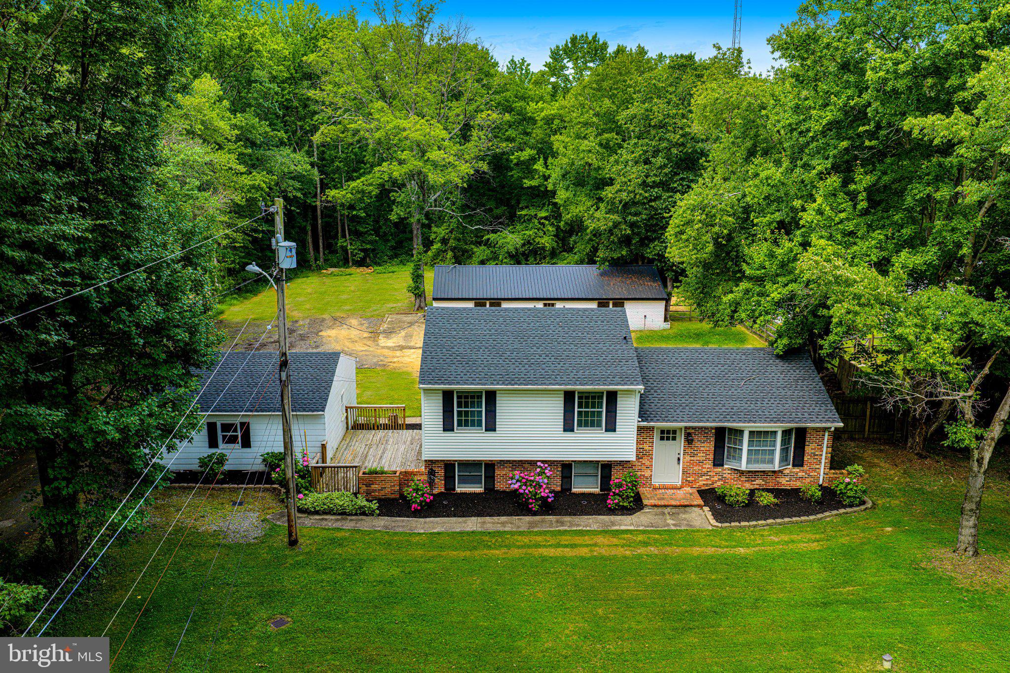 NEW ACTIVE DATE: JULY 24TH! Welcome to your own private retreat! Nestled on 1.13 peaceful acres surrounded by mature trees, this beautifully renovated property offers the perfect blend of timeless style, modern updates, and exceptional outdoor living. Renovated in approximately 2023 with luxury finishes throughout, this one-of-a-kind home is truly move-in ready.

The stunning kitchen is a showpiece featuring genuine Carrara marble countertops, a farmhouse sink, stainless steel appliances, built-in microwave, premium Rejuvenation unlacquered brass hardware, a large island, and breakfast area. 

The upstairs offers spacious bedrooms and a beautifully remodeled upper-level bathroom showcasing basketweave marble flooring, classic subway tile, modern vanity, linen closet, and a window for added natural light. 

The spacious walk-out lower level offers an expansive recreation room also perfect as a home office, fitness space, or playroom... as well as a modern farmhouse style half bath.

Additional features include gorgeous luxury vinyl plank flooring throughout- designed to resemble authentic wide-plank hardwood, soft gray painted interior doors that create a warm Modern Farmhouse/Boho aesthetic, arched doorways, designer lighting, under cabinet lighting and soft close cabinets in the kitchen, and a front load washer and dryer. 

Outdoor living is just as impressive with multiple areas designed for relaxation and entertaining, including a large two-tier deck, a charming courtyard-style deck, and a paver patio with fire pit nestled among beautiful azaleas—creating the perfect setting for gatherings or quiet evenings at home.

A rare highlight of the property is the incredible 24' x 48' outbuilding complete with electric and water. Whether you're looking for a workshop, hobby space, art studio, clubhouse, additional storage, or a place for your favorite projects, this versatile building offers endless possibilities. A detached two-car garage provides even more space for a workshop, storage, and/or parking.

Peace of mind with major improvements completed-  new roof on the home, detached garage, and outbuilding (approx. 2024-2025), hot water heater (approx. 2019-2020), and water softener system (approx. 2019-2020).

Offering the lifestyle of country living yet just minutes from I-95 and major commuter routes, this rare property delivers the perfect combination of privacy, convenience, timeless design, and endless possibilities. Homes with this level of renovation, acreage, and incredible outbuildings rarely become available—don't miss your opportunity to make this one yours!

*Some photos are AI Enhanced and Staged*