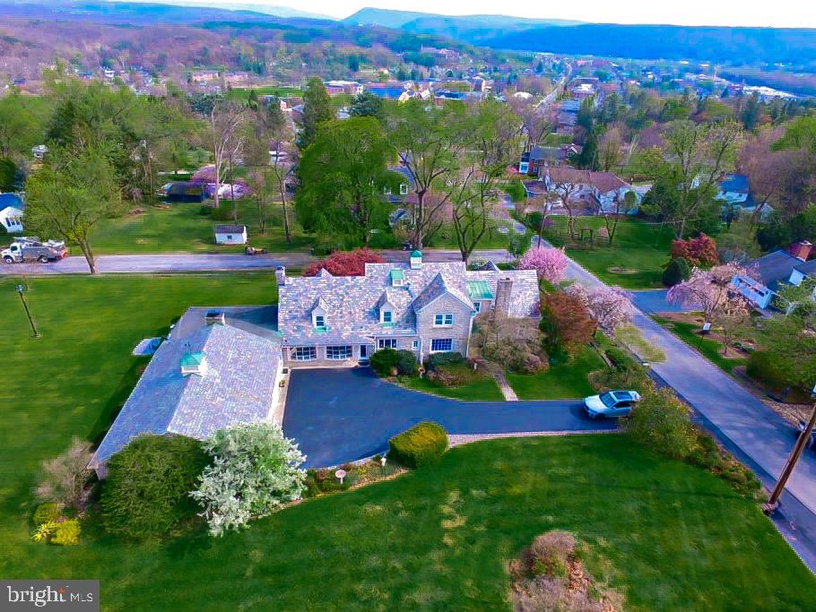 Perched atop the desirable Taylor Highlands neighborhood, this stately 4-bedroom, 4 bath home offers timeless elegance, quality craftsmanship, and unmatched character in every room. Situated on a spacious corner lot, the home combines classic architectural details with modern comforts, creating a truly exceptional living experience. Located near Juniata College, Penn Highlands Hospital, local schools, historic downtown district, and scenic walking trails, this property provides both convenience, charm and prestige. Its easy commute to State College makes it ideal for those seeking a peaceful retreat with access to nearby amenities.  The home’s stone exterior and slate roof showcase enduring craftsmanship, while seasonal colors from the beautifully landscaped property radiate through every window, filling the interior with natural light. Inside, spacious and elegant rooms flow seamlessly, offering a warm and inviting atmosphere. Ample closet space, including three cedar closets, ensures abundant storage throughout the home. The large sunroom, surrounded by windows and anchored by a stunning stone fireplace, provides the perfect setting for relaxation or entertainment. The finished basement extends the living space with another stone fireplace, a cozy TV room featuring a retro bar, and a large multipurpose area ideal for a family room, game room, or recreation space. A convenient ¾ bath and an abundance of closet space completes this versatile lower level. The oversized garage is a car enthusiast’s dream, equipped for detailing with heat, option for AC hookup, hot and cold water, and dual drains. For those seeking to customize, the adjoining room next to the kitchen offers potential to create a chef’s kitchen with a large island, expanded dining area, and mud/laundry room—endless opportunities await. A second stairway adds both function and charm to the home’s thoughtful layout. This distinguished property blends historic character, modern amenities, and a premier location—an exceptional opportunity to own one of Taylor Highlands’ most remarkable homes.