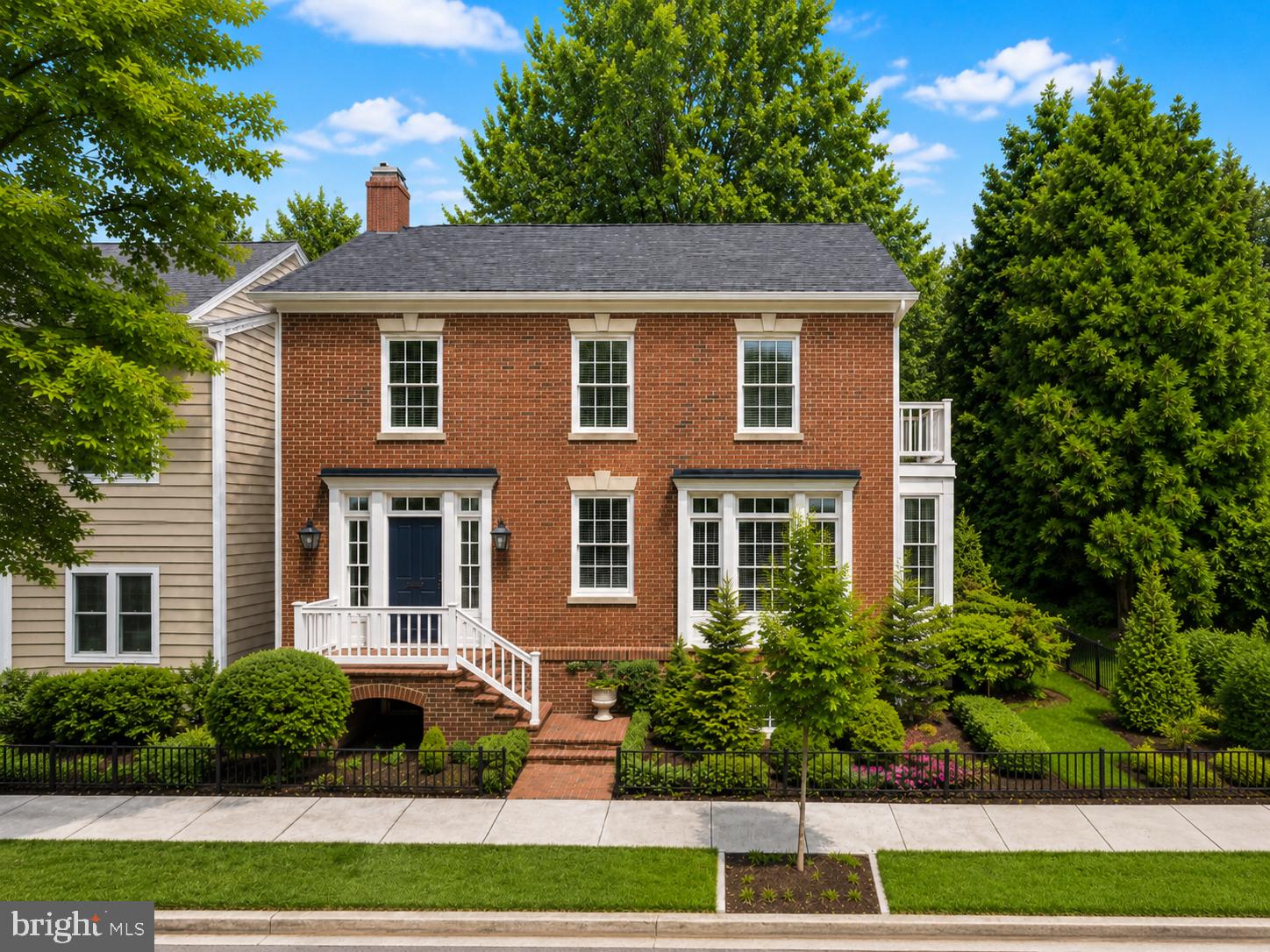 Perfectly located in the Old & Historic District of central Old Town, this 4-bedroom residence with attached garage offers a rare combination of historic setting, thoughtful design, and everyday convenience near Metro, restaurants, and shopping. Designed by Morris-Day Associates and constructed in 1994, this one-of-a-kind home is being offered for sale for the first time. The low-maintenance brick exterior features masonry on all sides, cast keystones, true divided-light windows, and Bevolo gas light fixtures at the front entrance. The attached side-load garage is finished with polished concrete floors, a Tesla charging station, custom built-in cabinetry, and pull-down access to a large storage area above.
Front, side, and rear garden areas are served by a zoned irrigation  system. A covered side porch with Ipe decking overlooks a private garden with stone wall seating, an arbor, and water feature.
Inside, the traditional floor plan is enhanced by four exposures, filling the home with natural light throughout the day. The main level features 9-foot ceilings, a rear staircase, hardwood flooring, and solid architectural detailing. A custom-designed and fabricated Indiana limestone fireplace serves as the focal point of the living room, framed by arched bookcases, a box beam ceiling, and columns.
French doors open to a Tanglewood conservatory with English ceiling blinds, heated slate floors, ceiling fan, and dedicated HVAC system. In the kitchen, limestone floors are complemented by natural cherry cabinetry, granite countertops, Sub-Zero refrigeration, and a Wolf gas range.
The upper-level primary suite features a vaulted ceiling with fan, private balcony, walk-in closet with washer/dryer hookup, and en suite bath with steam shower. Two additional bedrooms share a full bath, with a convenient laundry chute to the lower level.
The lower level offers a complete in-law suite with separate entrance, full kitchen, bedroom, full bath, and living room with French doors opening to the rear garden, with access to the garage and alley.  This home has no common wall with neighboring home and no HOA. Enjoy the quiet no bus line or cut through on a tree lined street just 1 block to historic  Robert E Lee's boyhood home and only a few blocks to the Potomac river and parks. Owner licensed real estate agent