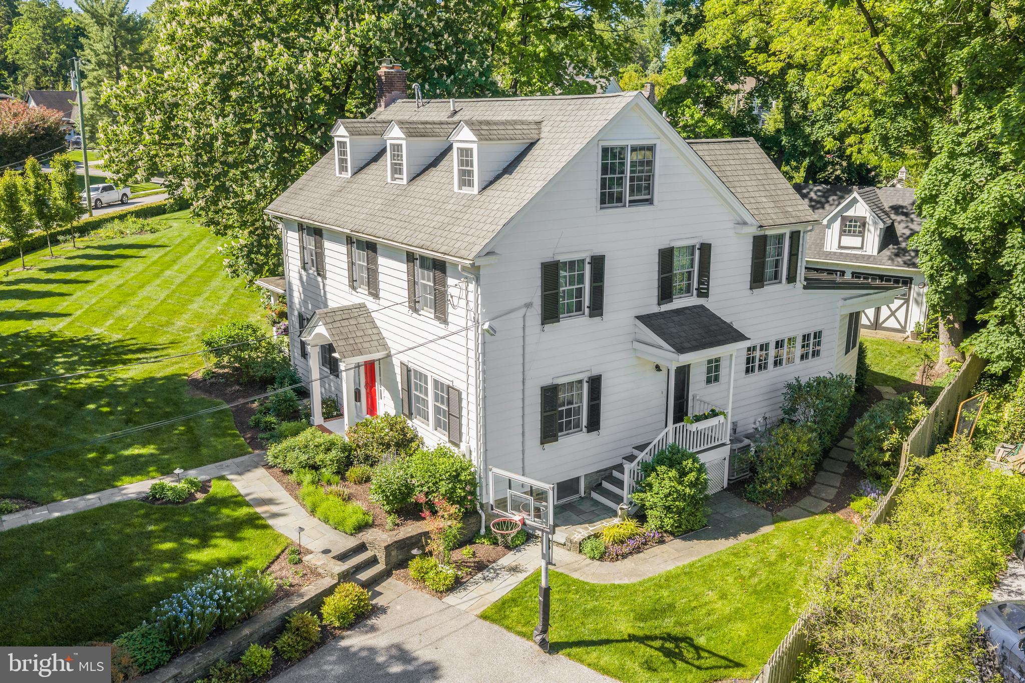 Welcome to 230 S Wayne Avenue — a beautifully updated 3-story Colonial nestled in the heart of prestigious South Wayne offering the ultimate in WALK TO WAYNE convenience. A charming white picket fence embraces the property while professionally landscaped grounds and perennial gardens provide color throughout the seasons creating captivating curb appeal. A covered Porch accessible from both the Living Room and Family Room creates exceptional circular flow ideal for everyday living and entertaining. Inside, gleaming hardwood floors, abundant natural light, and beautifully appointed spaces flow throughout the home’s gracious floor plan. Expansive Living and Dining Rooms create warm and inviting gathering spaces while the chef’s dream gourmet Kitchen features a commercial-grade 8-burner range with skillet and double ovens, soapstone countertops, and a custom island with a massive butcher block. The kitchen opens to a sunny breakfast space with built-in banquet overlooking the beautiful backyard and charming barn-like garage. Just off the back door is a custom-built Mudroom with beautiful built-ins and a conveniently located Powder Room creating the perfect everyday entry space. Just steps down from the kitchen is a spectacular Family Room addition with soaring ceilings and a dramatic wall of windows flooding the space with natural light. The Second Floor features 4 spacious Bedrooms including a luxurious Primary Suite with colorful designer bath featuring custom cabinetry, farmhouse sink, large walk-in shower, towel warmer, and separate his and hers walk-in closets. Two secondary Bedrooms are serviced by an updated Jack and Jill bathroom while an additional updated hall bath with tub/shower combination services the fourth bedroom. The fully finished Third Floor could easily function as a 5th Bedroom Suite and features a magnificent open room ideal for hangout space, playroom, media room, or workout area accented by exposed brick and numerous skylights. A private Office and Powder Room complete the level. A charming 2-story barn-like detached 2-car Garage provides endless opportunities for a future party barn, golf simulator room, private office, in-law or au pair space, or continue to use as abundant storage like the current owners. Perfectly positioned with sidewalks leading directly into downtown Wayne featuring some of the finest restaurants, boutiques, cafés, shops, parks, and train station on the Main Line, this exceptional home promises years of cherished memories in one of Radnor Township’s most sought-after neighborhoods. SHOWINGS START ON TUESDAY MAY 19th