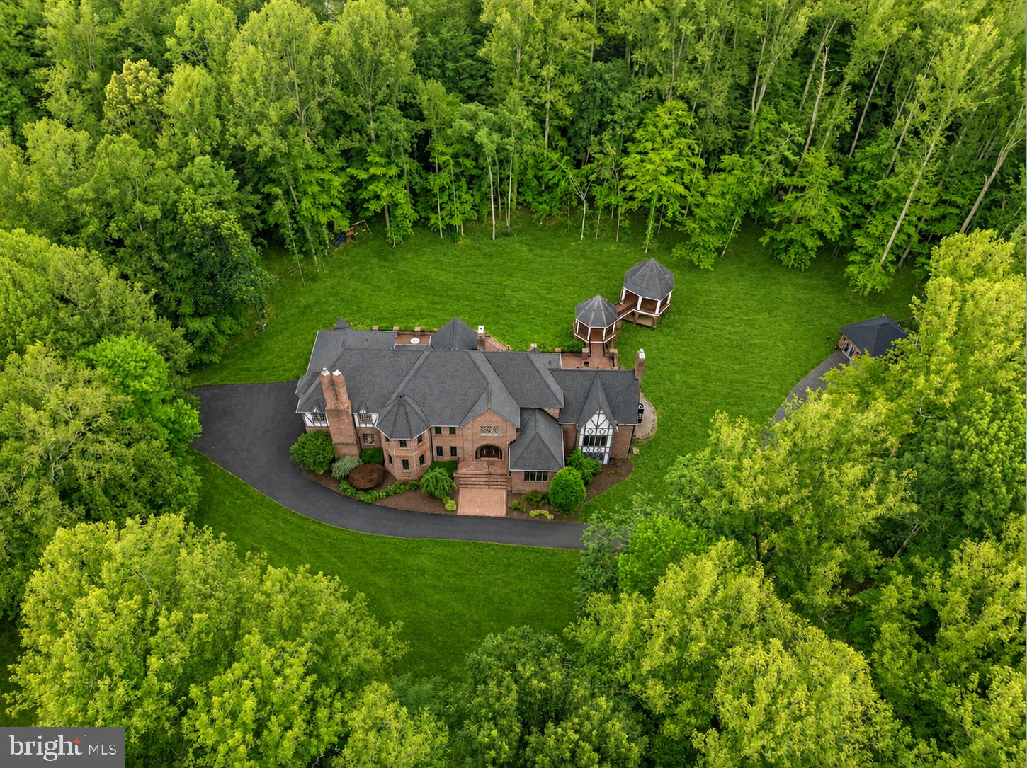JUST LISTED!! A rare opportunity to own a legacy estate in Fairfax Station's prestigious Dominion Valley Hunt community. Welcome to The Grand Tudor—an extraordinary double-gated (4BR/5.5 Bath) French Tudor estate set on five private acres, offering more than 8,000 square feet of reimagined luxury living, complete with a detached guest villa (1 BR/1FB).

Masterfully redesigned in a Transitional Heritage style, this remarkable residence blends timeless architecture with modern functionality. Extensive structural enhancements created the bright, open floor plan today's luxury buyers desire while preserving the home's original character and craftsmanship. Over $700,000 has been invested in renovations throughout the upper two levels and guest villa.

The main residence features soaring 10-foot ceilings, oversized windows, and expansive living spaces designed for both entertaining and everyday living. The West Wing showcases a ballroom, elegant parlor, and private library with custom built-ins. The East Wing offers an embassy-sized dining room, chef's kitchen, family room with fireplace, playroom, and oversized arrival center with laundry suite, powder room, and built-in lockers.

Timeless masonry craftsmanship defines the estate, from the all-brick main residence and detached villa to the grand double-gated entrances. The chef's kitchen is a showpiece featuring commercial-grade Sub-Zero, Wolf, and Cove appliances, a dramatic 14-foot quartz island, and a custom coffee and beverage station with wine refrigeration and ice maker.

A private owner's staircase leads to four spacious upper-level bedroom suites, each with beautifully renovated baths. The luxurious primary suite features vaulted ceilings, a fireplace, sitting area, dual walk-in closets, and a spa-inspired bath finished in Italian Carrara marble with dual vanities, bidet, and an expansive dual shower with multiple systems and 14 body sprays.

The walkout lower level is designed for entertaining, offering a recreation lounge with pre-wired Polk Audio surround sound, fourth fireplace, brick wine cellar, bar area, home gym or optional bedroom space, fifth full bath, second laundry area, and generous recreation space.

Outdoor living is equally impressive with over $100,000 in recent improvements, including a newly refinished 2,350 square-foot herringbone-pattern deck with dual covered gazebos overlooking a private wooded setting. A fully repaved driveway coming mid-July that connects both security gates and enhances the estate's grand arrival experience.

The newly renovated detached guest villa offers approximately 400 square feet of private hotel-style accommodations complete with kitchenette, full bath, Murphy bed, dedicated HVAC system, hardwired high-speed internet, and full utility services. Ideal for guests, an au pair, multigenerational living, or a private office retreat.

The rear grounds have been transformed through the removal of 55 trees and stumps, creating an expansive outdoor oasis with ample room for recreation, future pool construction, and outdoor entertaining. Pool plans are available upon request.

Recent capital improvements include new roofs on both the main residence and guest villa (2023), upgraded well and water treatment systems (2021), new HVAC systems, two new 50-gallon water heaters, and comprehensive preventative maintenance throughout ownership.  The estate is fully integrated with smart-home technology, featuring over 40 smart switches, three smart locks, four smart thermostats, and multiple internet hubs providing seamless connectivity throughout both residences.

Enjoy the privacy and tranquility of a five-acre estate while remaining just off 123, 30 minutes from Washington, D.C., with convenient access to major commuter routes, shopping, dining, and top-rated schools. The Grand Tudor is a turnkey private estate that seamlessly combines timeless French Tudor architecture, modern luxury, exceptional craftsmanship, and resort-style living.