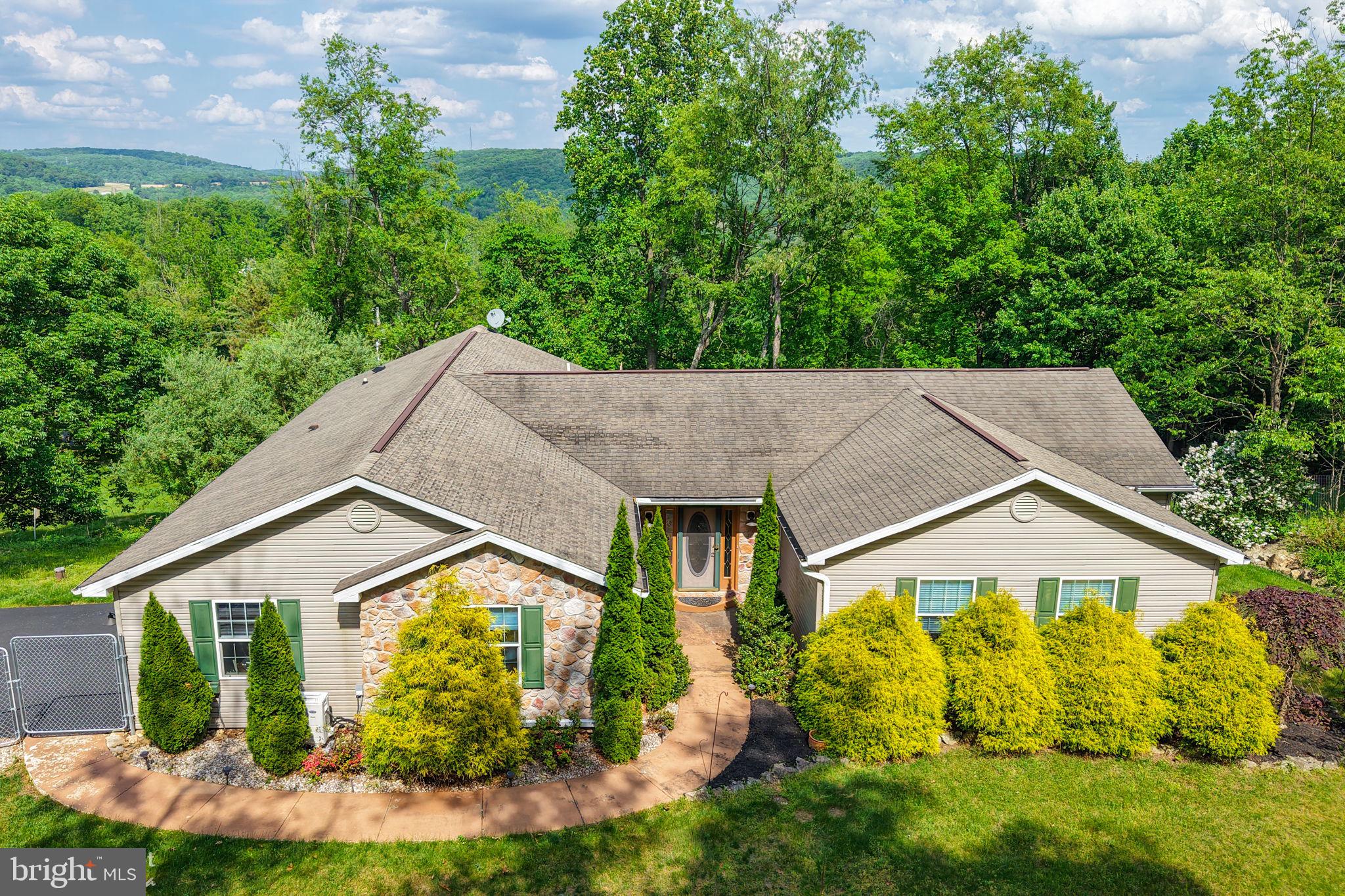 Welcome to your own private woodland retreat! Nestled among 3 acres of mature trees in scenic Berks County, this custom 3 Bedroom, 3 bath ranch offers the rare opportunity to enjoy peaceful country living without sacrificing comfort or convenience. With over 3,500 square feet of beautifully finished living space, this home was designed for both relaxation & entertaining. Rich Brazilian cherry floors on the main level, spacious gathering areas on both floors & walls of windows create a warm and inviting atmosphere throughout. The finished walk-out lower level opens to a private patio & features a wet bar, full Bath and abundant flexible space, perfect for a home office, or for year round hosting of family and friends. The primary suite is a true escape, boasting a luxurious spa bath with a dramatic pedestal soaking tub, separate vanities & an oversized walk-in shower with pebble stone flooring. Step outside to the low-maintenance Trex deck & enjoy breathtaking views of your own wooded paradise, where nature and privacy surround you in every season. An attached garage/workshop, carport, two sheds, parking for a boat or camper, whole-house generator, new gas heating system, and all appliances included make this property as practical as it is beautiful. Whether you're sipping coffee while watching wildlife, entertaining on the deck, or enjoying the serenity of your wooded acreage, this remarkable property offers a lifestyle that is increasingly hard to find. Nature, privacy, and comfort await.