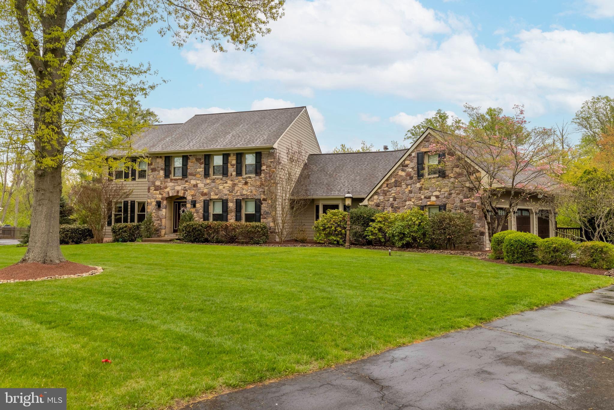 Exceptional Estate-Style Center Hall Colonial in the High Spires community on Over an Acre. Set on a beautifully manicured 1+ acre lot within the highly regarded Council Rock School District, this expansive 5-bedroom, 3 full and 2 half bath center hall colonial delivers the space, finishes, and amenities expected at this level. The home’s exterior immediately impresses with vinyl cedar shake siding, a stone facade, professional landscaping, and an expanded driveway leading to a 3-car garage. Inside, a grand foyer with double coat closets opens to a thoughtfully designed layout. Formal living and dining rooms feature crown molding, chair rail, and glass French doors, offering refined spaces for entertaining. A versatile bonus room with closet—currently used as a home office—adds flexibility. The heart of the home is a truly oversized kitchen, equipped with granite countertops, tile backsplash, double wall ovens, pantry storage, and a large center island with breakfast bar. A dedicated coffee/serving bar and a spacious dining area with sliding doors lead to a two-tier composite deck—ideal for indoor-outdoor living. The adjoining great room is both warm and dramatic, showcasing exposed wood ceiling beams, a stone fireplace with slate hearth and wood-burning insert, a bay window that brings in abundant natural light, and an adjacent wet bar with wine refrigerator. Upstairs, the primary suite offers a private retreat with recessed lighting, crown molding, ceiling fan, and a custom walk-in closet complete with center island, shelving, and built-ins. The en-suite bath features a jetted tub, stall shower, and tile flooring. Three additional bedrooms provide ample space, including a fifth bedroom with its own entrance—perfect for guests, an in-law suite, or extended living—paired with a beautifully finished full bath. A second-floor laundry room adds everyday convenience. The fully finished walkout basement expands the living space significantly, offering a game room, exercise room, lounge, additional sitting area, plus dedicated storage and workspace. Outdoors, the property is designed for entertaining—featuring an in-ground pool, PA Bluestone patio, outdoor bar with lighting and stone finish. Additional highlights include hardwood flooring throughout the first floor, solid wood interior doors, and multiple well-appointed living and entertaining spaces throughout. A rare combination of size, functionality, and upgraded amenities—this is a standout property in today’s market.