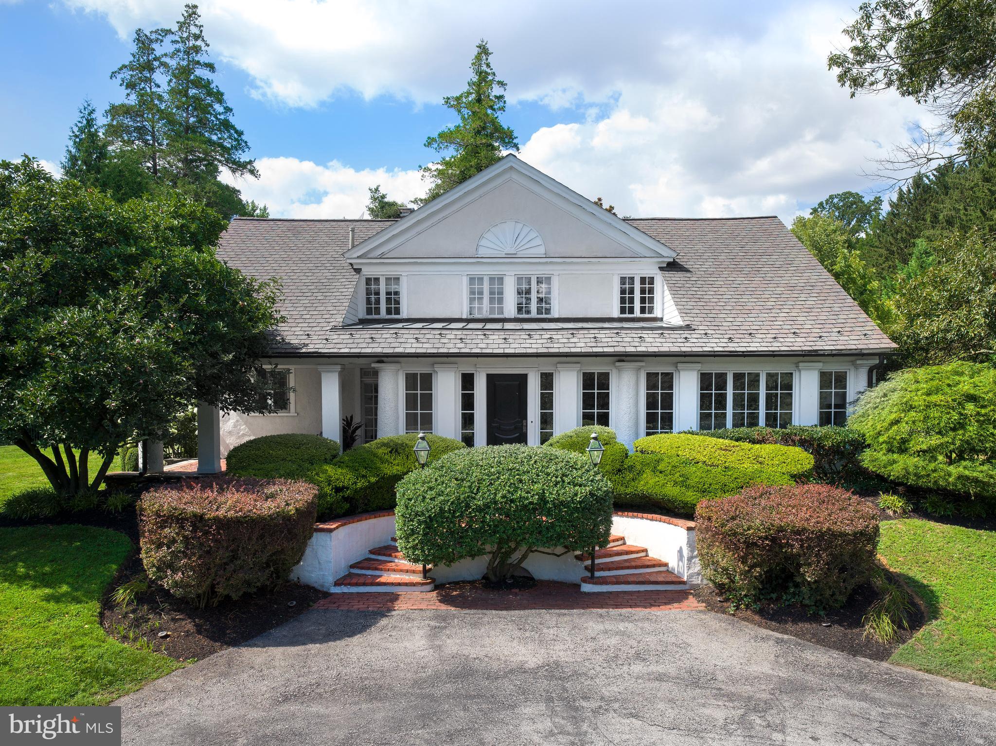 Set well back from the road, enter past mature bushes and trees down a driveway that opens to majestic estate-like grounds. This completely renovated home offers privacy and serenity in Villanova's estate area near Cedar Lane and Appleford. The property embodies exquisite style and design, featuring high-end finishes that align with the preferences of today’s buyers. Every detail was selected to create a blend of modern luxury and timeless charm. From the elegant marble countertops and custom cabinetry in the kitchen to new hardwood flooring throughout, the home exudes sophistication while maintaining a warm and inviting atmosphere. The extensive updates have transformed this property into a move-in-ready masterpiece, offering the perfect fusion of modern functionality and classic appeal. The estate-like grounds provide an idyllic retreat, offering a wealth of outdoor amenities, including a saltwater pool with newer hardscaping, an outdoor shower, a basketball court, a treehouse, multiple patios, and a pergola, —perfect for relaxation and entertainment. The interior of the home is equally impressive, starting with a foyer featuring marble floors and French doors leading to a porch with a brick floor. Elegant details such as custom molding in the living room, dining room, and foyer, original beams on the living room ceiling, and a decorative plaster fireplace with a herringbone brick hearth add historical charm to the modernized space. The custom Chippendale staircase railing and new hardwood floors, which continue throughout the first floor and primary bedroom, further enhance the home's aesthetic. At the heart of the home is the stunning chef’s kitchen, featuring Calcutta gold marble countertops and backsplash, painted inset shaker cabinets, 2 large islands, and a coffee bar. High-end appliances include a Viking stove, KitchenAid double ovens with convection, a Subzero refrigerator, and a Bosch dishwasher. The kitchen’s luxurious fixtures and lighting from Restoration Hardware and Rohl elevate the space, while large pantry cabinets provide ample storage. The seamless flow from the kitchen to the dining room and beyond offers convenience. The family room is a true showstopper, with 12-foot ceilings, custom built-in bookcases, thick crown moldings, and a wood-burning fireplace. This room features 2 sets of French doors leading to the pool area and a 3rd set that opens to the yard. The sunroom, with original brick herringbone flooring, built-ins, and French doors leading to stone steps and the side yard, is another highlight. The powder room has been beautifully updated with Serena & Lily wallpaper, a herringbone marble floor, and new fixtures, while the mudroom, complete with built-in cubbies, provides access to the 3-car garage and driveway. Upstairs, the primary bedroom is a luxurious retreat with a barrel ceiling, a Palladian window and 4 spacious closets. The primary bathroom includes marble floors, a jacuzzi tub, and shower, creating a spa-like experience. The additional bedrooms are generously sized, featuring newer carpets, large closets, and charming details like deep window sills. One bedroom includes a princess bathroom with a tub, while another serves as a home office. The upstairs also features a laundry area, 2 hall linen closets, and a skylight that fills the space with natural light. Additional updates include a new roof (2017), new HVAC and furnace systems, a tankless water heater, a new oil tank, and modernized pool equipment, including a new motor, salt cell, and control board for the saltwater pool. The home also boasts new interior paint throughout the main level and upstairs, new light fixtures, and additional trim in the formal living and family rooms, stairway, foyer, and powder room. This home seamlessly blends historical charm with modern updates to provide a one-of-a-kind living experience.