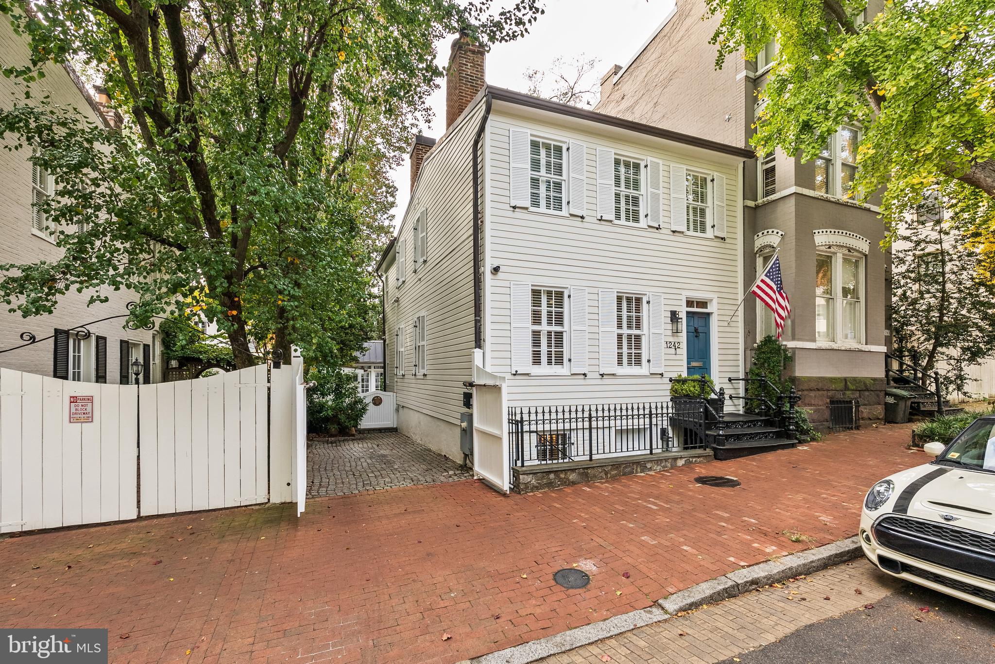 Nestled on a picturesque tree-lined street in the heart of Georgetown, this beautifully renovated semi-detached Federal residence, built circa 1830, is a rare gem featuring a thoughtfully updated open floor plan and a charming detached carriage house.  The residence seamlessly combines historic elegance with modern-day amenities for sophisticated living and entertaining. The main level offers a spacious, open layout designed for entertaining, with lovely scaled rooms that are bathed in natural light from three exposures. Attractive hardwood floors stretch throughout, adding warmth and character. A gracious entry foyer welcomes you into the sophisticated living room, where high ceilings and a central fireplace with an intricately detailed wooden mantel create an inviting ambiance. Moving through the formal dining room, you’ll find the fully renovated gourmet kitchen, equipped with a large peninsula with a breakfast bar, high-end appliances, custom cabinetry, and a spacious pantry. The kitchen space is generous and offers the ability to have a breakfast table and/or sofa seating. There are multiple doors with transom windows leading to the rear terrace and garden, seamlessly blending indoor and outdoor spaces. For added convenience, a powder room is located on this level. On the second floor, the luxurious primary suite occupies a private position at the back of the house. Generous in scale, it opens to a Juliet balcony that overlooks the serene garden. This suite features an impressive walk-in closet and a spa-inspired bathroom, complete with dual vanities, a spacious shower with a bench and multiple fixtures, and a separate water closet. Also on this level is a second spacious bedroom, adorned with three large windows and charming built-ins. This bedroom shares the floor with a full bathroom and a large hall closet. The lower level offers a versatile recreation room or office with built-in shelving, ideal for work or relaxation. This level also includes a third bedroom with a decorative fireplace, built-ins, and a private entrance from the front of the house, making it perfect for guests. A full bathroom and a built-in bar with a wine refrigerator add to the lower level’s appeal, along with a laundry room that includes a utility sink and ample storage. The outdoor space is equally impressive, with a private rear terrace and beautifully landscaped gardens that are perfect for entertaining. A breezeway leads to the detached and beautifully finished carriage house, which provides additional living space with a large sitting area, fireplace, built-in desk with office storage, bathroom, and a wet bar. For added convenience, there is a gated parking area that can accommodate one car, as well as a charming storage shed. This exceptional Georgetown residence offers an unparalleled blend of historic charm and modern conveniences, making it an ideal home for both intimate living and elegant entertaining. Georgetown’s prime location places residents just minutes from the White House and key downtown DC destinations, offering unparalleled convenience for city living. Georgetown’s easy access to major routes provides a straightforward commute to both Reagan National and Dulles International Airports, making travel seamless for residents.