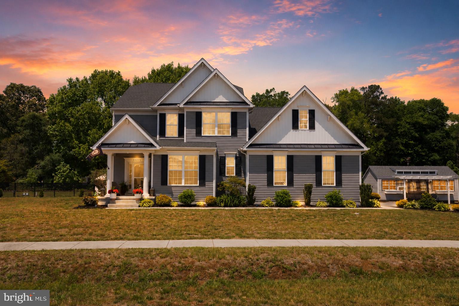 Looking for a home that offers easy access to the Delaware beaches without the everyday congestion? Welcome to 32273 Janice Lane — ideally located with a Georgetown address, yet conveniently central to Millsboro, Long Neck, and surrounding coastal communities.

From the moment you step inside, this beautifully designed home feels like something straight from the pages of a magazine. Offering 4 bedrooms with the potential for a 5th bedroom (septic approved for 4), the thoughtfully designed floor plan combines elegance, comfort, and functionality throughout.

The open-concept living area is filled with natural light from dramatic floor-to-ceiling windows and features soaring ceilings, luxury vinyl plank flooring, custom picture frame molding, gas fireplace, custom blinds, and a spacious dining area. The kitchen is truly the heart of the home with stainless steel appliances, gas cooktop, wall oven, under-cabinet lighting, pantry, abundant storage, and a stunning hammered copper farmhouse sink complemented by matching pendant lighting over the island.

The first-floor primary suite provides a private retreat complete with dual walk-in closets and a luxurious ensuite bath featuring a tiled stall shower, LED mirror, and separate water closet. Also on the main level are a dedicated office, laundry room, and convenient half bath.
Upstairs, a spacious loft overlooks the main living area and leads to three additional bedrooms, a full bath, and an oversized bonus room with extra storage space — perfect for a media room, playroom, guest suite, or optional fifth bedroom.

Step outside into your own backyard oasis where established landscaping, mature trees, and peaceful outdoor living spaces create the perfect setting for relaxing or entertaining. Enjoy the soothing waterfall and koi pond, paver patio, hot tub, fenced yard, and large storage shed ideal for gardening, hobbies, or additional storage. An attached garage and spacious paved driveway complete the package.

This exceptional property combines luxury finishes, flexible living space, and a prime location