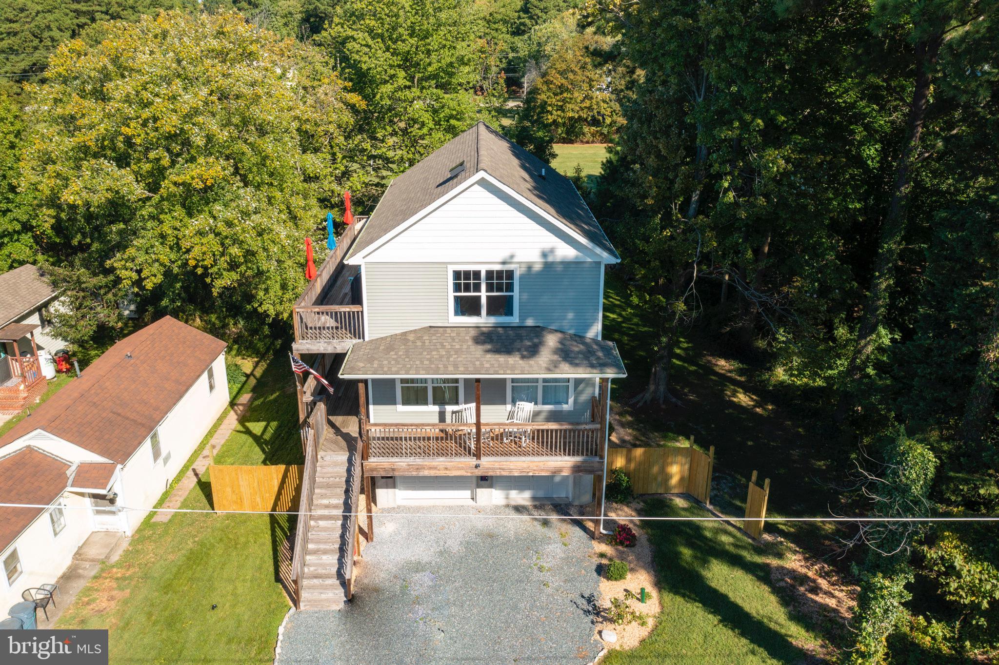 Deck was washed and stained on 5/20/26! Built in 2018, this custom coastal raised home is ideally located just one block from the Chesapeake Bay, offering the perfect blend of relaxation, recreation, and investment potential. Enjoy easy access to Rock Hall’s 12 marinas, Ferry Park Beach, local restaurants, shops, and charming downtown—all just a short walk, bike ride, or drive away. Nature lovers will appreciate the close proximity to Eastern Neck Island National Wildlife Refuge, where you can explore by foot, kayak, or bike.

Designed for both everyday living and entertaining, the home features an oversized two-car garage with abundant parking—ideal for storing kayaks, paddleboards, bikes, jet skis, and more. The spacious, private backyard sets the stage for gatherings with a fire pit and over 1,000 square feet of wraparound decking invites you to take the party upstairs. A covered porch offers the perfect spot to relax and enjoy summer storms or gentle coastal breezes, and the outdoor shower makes rinsing off after a day on the Bay a breeze.

Inside, you’ll find beautiful hardwood floors throughout, generously sized bedrooms, and a thoughtfully designed layout. The primary suite includes dual closets—one being an oversized walk-in—a full en-suite bath with tub/shower combo, and private deck access complete with a TRX workout area. The main living level showcases a bright, open-concept floor plan with stunning 360-degree views, ideal for entertaining. The top level features stainless steel appliances, granite countertops, and walls of windows that flood the space with natural light and capture glimpses of the Bay.

Multiple sliding glass doors on every level seamlessly connect indoor and outdoor living, making the expansive decks a true extension of the home.

Furnishing will be offered to be purchased making this turnkey, this property also boasts a proven rental history with three years of returning Airbnb and VRBO guests—providing excellent income potential for the weeks you’re not enjoying it yourself. Annual income details available upon request.

Don’t miss this exceptional opportunity to own your slice of the Bay lifestyle!