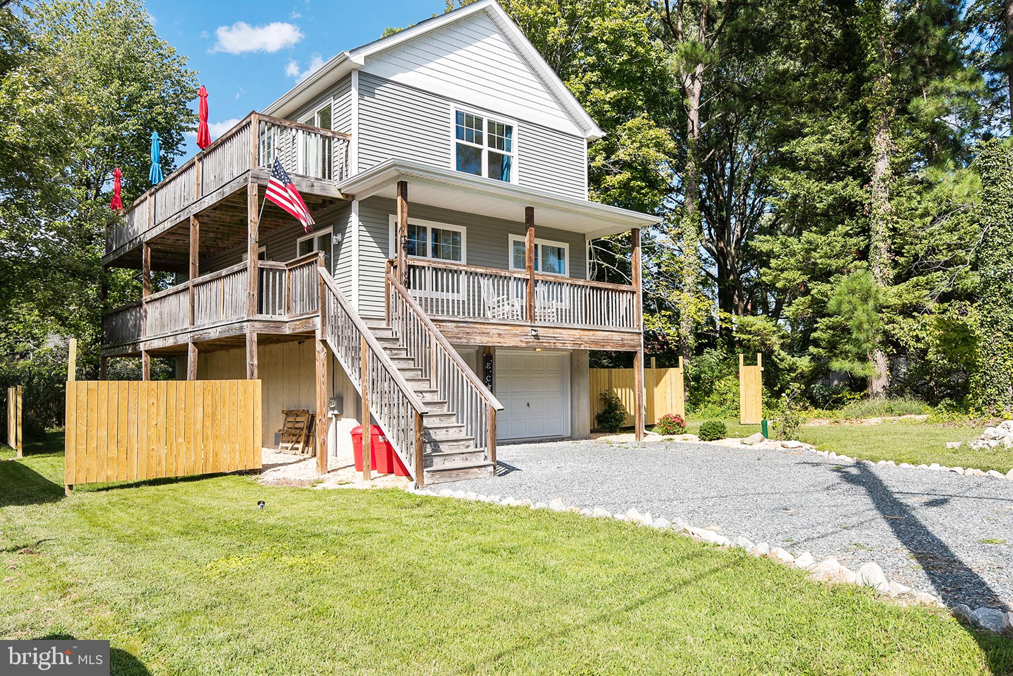 Deck was washed and stained on 5/20/26! Built in 2018, this custom coastal raised home is ideally located just one block from the Chesapeake Bay, offering the perfect blend of relaxation, recreation, and investment potential. Enjoy easy access to Rock Hall’s 12 marinas, Ferry Park Beach, local restaurants, shops, and charming downtown—all just a short walk, bike ride, or drive away. Nature lovers will appreciate the close proximity to Eastern Neck Island National Wildlife Refuge, where you can explore by foot, kayak, or bike.

Designed for both everyday living and entertaining, the home features an oversized two-car garage with abundant parking—ideal for storing kayaks, paddleboards, bikes, jet skis, and more. The spacious, private backyard sets the stage for gatherings with a fire pit and over 1,000 square feet of wraparound decking invites you to take the party upstairs. A covered porch offers the perfect spot to relax and enjoy summer storms or gentle coastal breezes, and the outdoor shower makes rinsing off after a day on the Bay a breeze.

Inside, you’ll find beautiful hardwood floors throughout, generously sized bedrooms, and a thoughtfully designed layout. The primary suite includes dual closets—one being an oversized walk-in—a full en-suite bath with tub/shower combo, and private deck access complete with a TRX workout area. The main living level showcases a bright, open-concept floor plan with stunning 360-degree views, ideal for entertaining. The top level features stainless steel appliances, granite countertops, and walls of windows that flood the space with natural light and capture glimpses of the Bay.

Multiple sliding glass doors on every level seamlessly connect indoor and outdoor living, making the expansive decks a true extension of the home.

Furnishing will be offered to be purchased making this turnkey, this property also boasts a proven rental history with three years of returning Airbnb and VRBO guests—providing excellent income potential for the weeks you’re not enjoying it yourself. Annual income details available upon request.

Don’t miss this exceptional opportunity to own your slice of the Bay lifestyle!