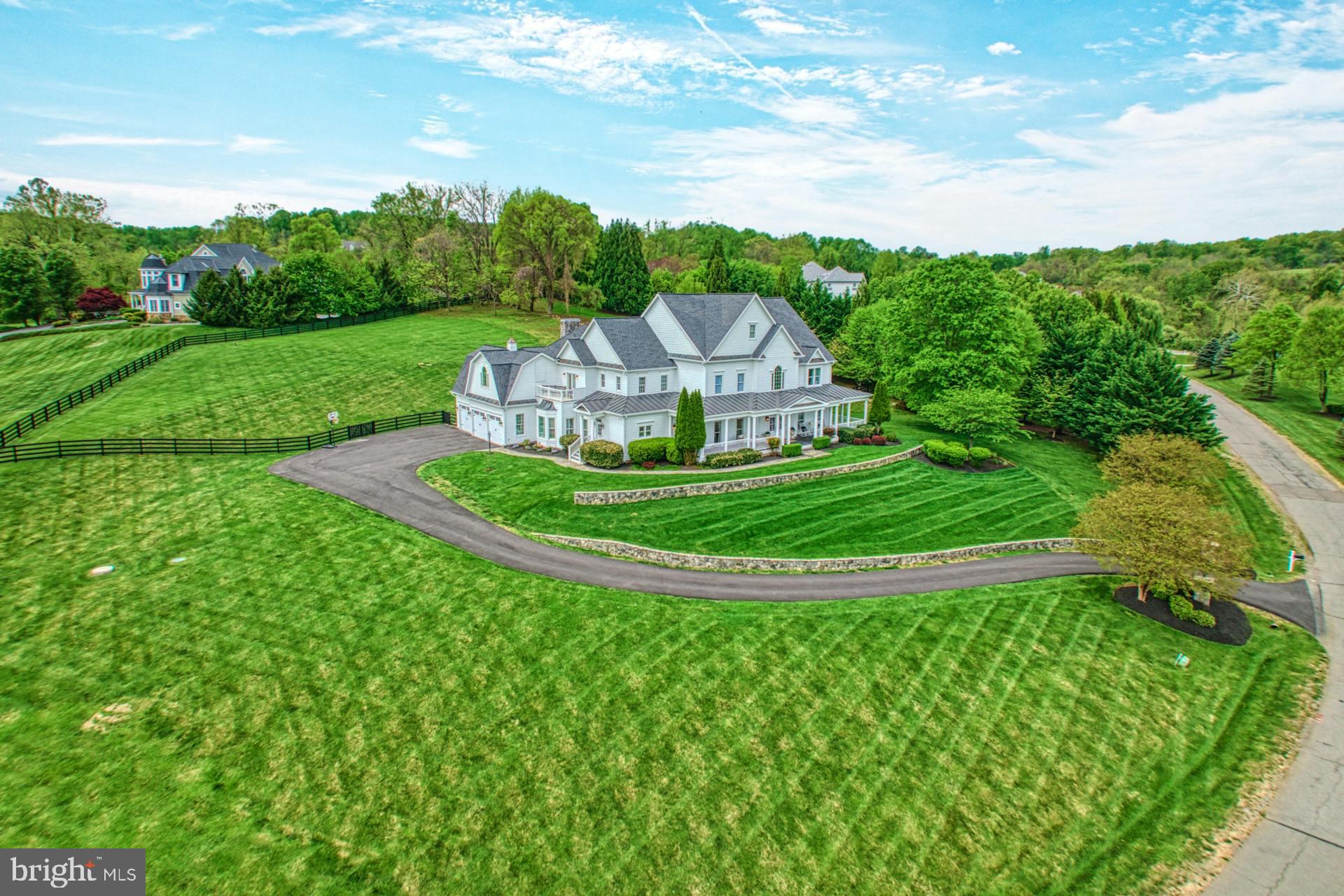 In distinguished Beacon Hill, where scenic grounds feature homes of traditional and custom design, this sunlit farmhouse beauty sits hill-top, as enviable cul-de-sac-privacy leads to your sweeping stone-lined welcome. Originally constructed and recently polished with high-end finishes, your memories to come will enjoy a backdrop of wide-plank hardwoods, encased transitions, field-stone fireplaces, and the charming architectural detailing of alcoves, thoughtful built-ins, and handcrafted ceilings. Unwind the day’s cares and entertain within grand and cozy living vistas near your kitchen of provincial personality. Here, homework can be completed at the nearby business nook, while dinner and sweets for celebrations are prepped with the help of beveled stone countertops, endless glazed cabinetry, butlers pantry, and centerpiece range. Practice yoga or train upstairs in the window-lined gym, let the cheerful mudroom prep outings, unwind with friends on the wrap-around porch, and host luncheons on the
patio where three acre grounds will have you planning the pool of your dreams. Five bedrooms, plus over seven baths, care for winding down the day. While the rare main-level suite is perfect for multi-generational long-term guests, your impressive primary escape both invites you to stay and readies evenings-out with its fireplace-warmed sitting room, dual closets, and spa-like bath. While touring, ask about upgrades including new roof, and visit the lower level where a gorgeous place for recreation awaits with stunning modern wet bar, theater, full bath, and flex/storage spaces. From home, enjoy Beacon Hill’s shaded walking trails, or take a favorite vehicle from your three car garage toward historic downtown Leesburg, OneLoudoun, IAD, local eateries, shops, and all Horse and Wine Country has to offer.