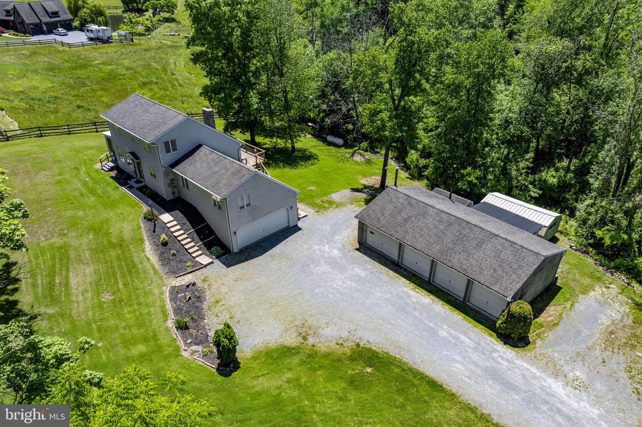 Charming Saltbox style 2-story on 1.3 Acres with Exceptional Living Space and Detached 4-Car Garage:  Nestled on a picturesque 1.3-acre lot, this distinctive 2-story home offers approx. 3244 SF total finished living space blended rustic charm with spacious comfort. The inviting great room features vaulted ceilings, exposed wood beams, lots of natural light, and a stunning floor-to-ceiling stone wood-burning fireplace that creates an inviting atmosphere. The kitchen provides ample workspace and flows into the great room and dining area. The sunroom provides a space where peaceful views of the property can be enjoyed year-round. The main level also includes a bedroom and full bath. Upstairs, you'll find 2 bdrms and an additional full bath. The finished daylight lower level expands the living area with a large family room, wood/coal stove, wet bar, and a third full bathroom- perfect for entertaining or extended living arrangements. Heating is provided by an efficient electric heat pump system with supplemental propane hot water heat for added comfort during colder months. Outdoor amenities are impressive! In addition to the attached two-car garage, the property features a substantial 24' x 45' detached 4-car garage with bathroom, electric, and wood stove, offering possibilities for hobbyists, contractors, or vehicle enthusiasts.  Air compressor is included. Additional 10 x 18 storage off the back of the garage and two storage sheds (12 x 20 and 10 x 6). Enjoy outdoor living on the expansive 42' x 10' deck and patio below, all overlooking the backyard. A generous driveway provides ample parking. This unique property offers a combination of character, functionality, and space both inside and out!