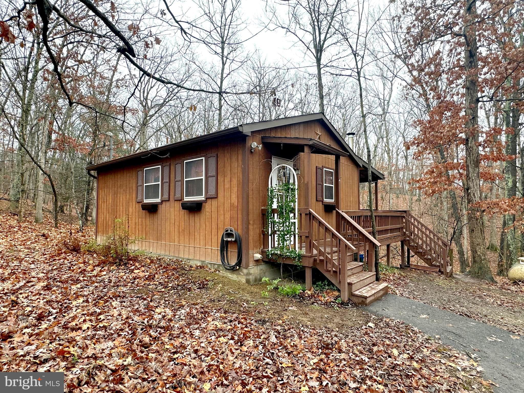 Resting on 2.32 acres in Sleepy Creek Mountain Retreat, you will find this quiet & cozy, fully furnished 1 bedroom, 1 bath home.  Approaching the property, you'll be greeted by the wooded lot, full of mature trees as well as the large wrap-around deck overlooking the side and rear of the property.  Entering the front door, you'll find a combination kitchen/living/dining area with exposed center beam and cathedral ceiling.  Laminate plank flooring is throughout this area as well as a corner wood stove.  The full bath/laundry room adjoins as well.  Walk out the back door to enjoy the seclusion, privacy and view from the large covered rear deck.  The bedroom also adjoins the living room area and features laminate plank flooring as well.  Through the bedroom, you'll find the beautiful sunroom with full height wrap-around windows as well as a sliding door for additional access the rear deck.  The size and location of this property is ideal for a budget minded buyer as well as a possible get-away property.  Central air makes summer time living a "breeze" and the wood stove (as well as central heat and wall units) give it that warm winter charm.  All furniture and furnishings convey with this very clean and well-kept property.  The additional shed provides ample storage.  3 hour advanced notice for showings due to large dogs - weekends are usually best for showings.