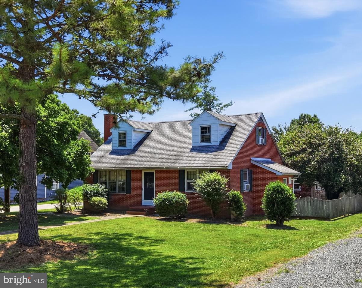 Sweet corner property in downtown Rock Hall, right on the 4th of July parade route! Just two blocks from the Rock Hall Harbor/ Chesapeake Bay. A welcoming home with a spacious kitchen and formal dining room, or enjoy meals outside in the fenced-in back yard! The large living room has hardwood floors and a wood stove for cozy winter nights. This home features a hard to find first-floor primary bedroom! Upstairs offers two additional bedrooms, a full bath, and an additional office or activity room. 
The home is situated on a large corner lot, set back from Main St., offering privacy and nice yard space. The charming garage with a loft is a great space for storage or a workshop. Close to all Rock Hall has to offer: marinas, shops, restaurants, and the Chesapeake Bay! This popular vacation rental could continue as an income producer but would also make a fantastic full-time residence. Being sold turn-key, just unpack your bags and enjoy. The homes hot water heat has been updated, zoned to both floors. Tankless hot water heater.