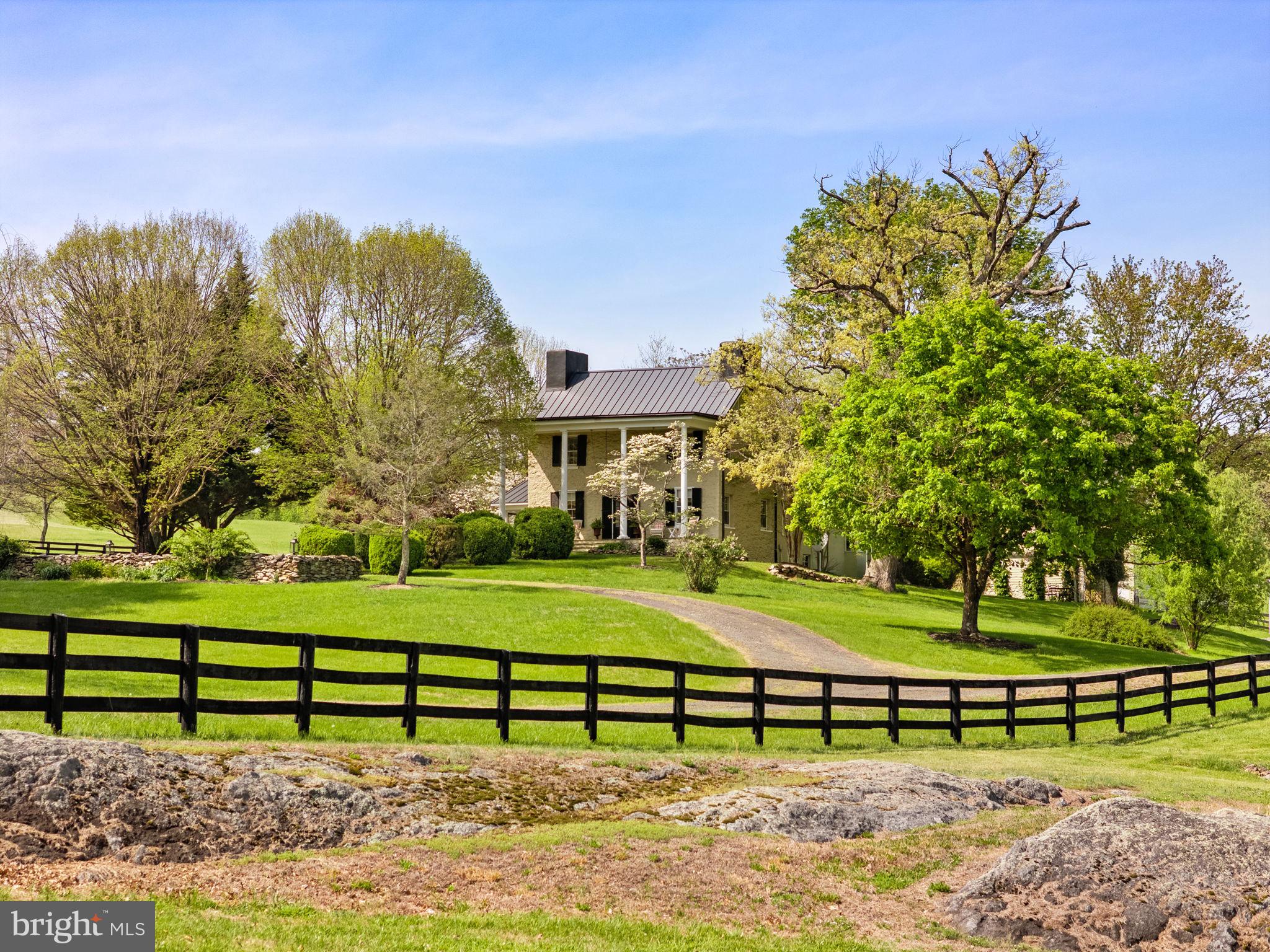 “Willow Run” is a truly enchanting country estate, steeped in history and timeless elegance. The original residence, dating to circa 1812 and masterfully constructed of stone and stucco by Mason Hirst, has been thoughtfully expanded over the years—most notably in 1880 and 1970—and exquisitely updated by its current stewards to blend historic charm with modern refinement.
Inside, the home offers 3 bedrooms and 2½ baths, where rich wood floors, four distinctive fireplaces, and beautifully proportioned rooms create a warm and inviting atmosphere. Sunlight pours into the gracious living spaces, which open effortlessly to a screened-in side porch and an expansive terrace—perfect for relaxed outdoor living and entertaining. A heated in-ground pool completes this idyllic setting, all framed by sweeping, panoramic views of the surrounding countryside.
The property’s additional improvements are equally compelling. A charming guest house, featuring 2 bedrooms, 1 bath, and soaring vaulted ceilings, provides a welcoming retreat for visitors. A spacious 3-car heated garage offers both convenience and utility. The striking bank barn, with its 4 stalls and tack room, is a testament to the estate’s rich agricultural heritage and equestrian potential.
Encompassing 94.65 breathtaking acres, the land unfolds as a harmonious blend of open and wooded terrain. Two serene, spring-fed ponds reflect the sky, while 27 acres of mature woodland offer privacy and natural beauty. The balance of the acreage is devoted to gently rolling pasture, enclosed by classic board fencing and complemented by a run-in shed—ideal for horses or livestock.
Adding to the property’s undeniable charm are a hill top cabin with exposed beams and phenomenal eastern views, picturesque stone spring house and the romantic remnants of a historic summer kitchen, now transformed into a garden sanctuary anchored by a rustic stone fireplace.
Impeccably maintained and rich in character, “Willow Run” represents a rare opportunity to own a storied and sophisticated estate in a premier Fauquier County location—where history, beauty, and tranquility converge.