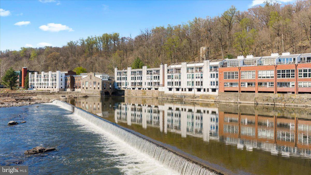 Experience the pinnacle of waterfront luxury at The Waterworks, an iconic, masterfully restored historic mill nestled between the tranquil Delaware Canal and the majestic Delaware River in downtown New Hope, PA. This rare, multi-level 2-bedroom, 2-bathroom condominium perfectly balances rich architectural heritage with modern sophistication. Secure lobby access and two highly coveted, dedicated garage spaces offer the ultimate peace of mind for a prestigious primary residence or a seamless, lock-and-leave weekend sanctuary. Inside, a sun-drenched open floor plan seamlessly blends indoor elegance with spectacular outdoor vistas through expansive windows. The meticulously curated space features a high-end gourmet kitchen designed for effortless entertaining, while authentic wood-burning fireplaces in both the living room and primary suite provide a warm, sophisticated ambiance. The upper-level primary sanctuary steps out onto a private riverfront balcony, offering an unmatched, exclusive vantage point for quiet morning coffees or sunset river views. Beyond your walls, an incomparable lifestyle awaits with the Delaware Canal State Park towpath directly at your doorstep for immediate hiking, biking, or kayaking. Leave your vehicles parked securely, as you are a mere stroll away from fine dining, world-class art galleries, and the historic Bucks County Playhouse in downtown New Hope and Lambertville, NJ. This is more than a residence; it is a rare opportunity to own a piece of Bucks County's heritage.