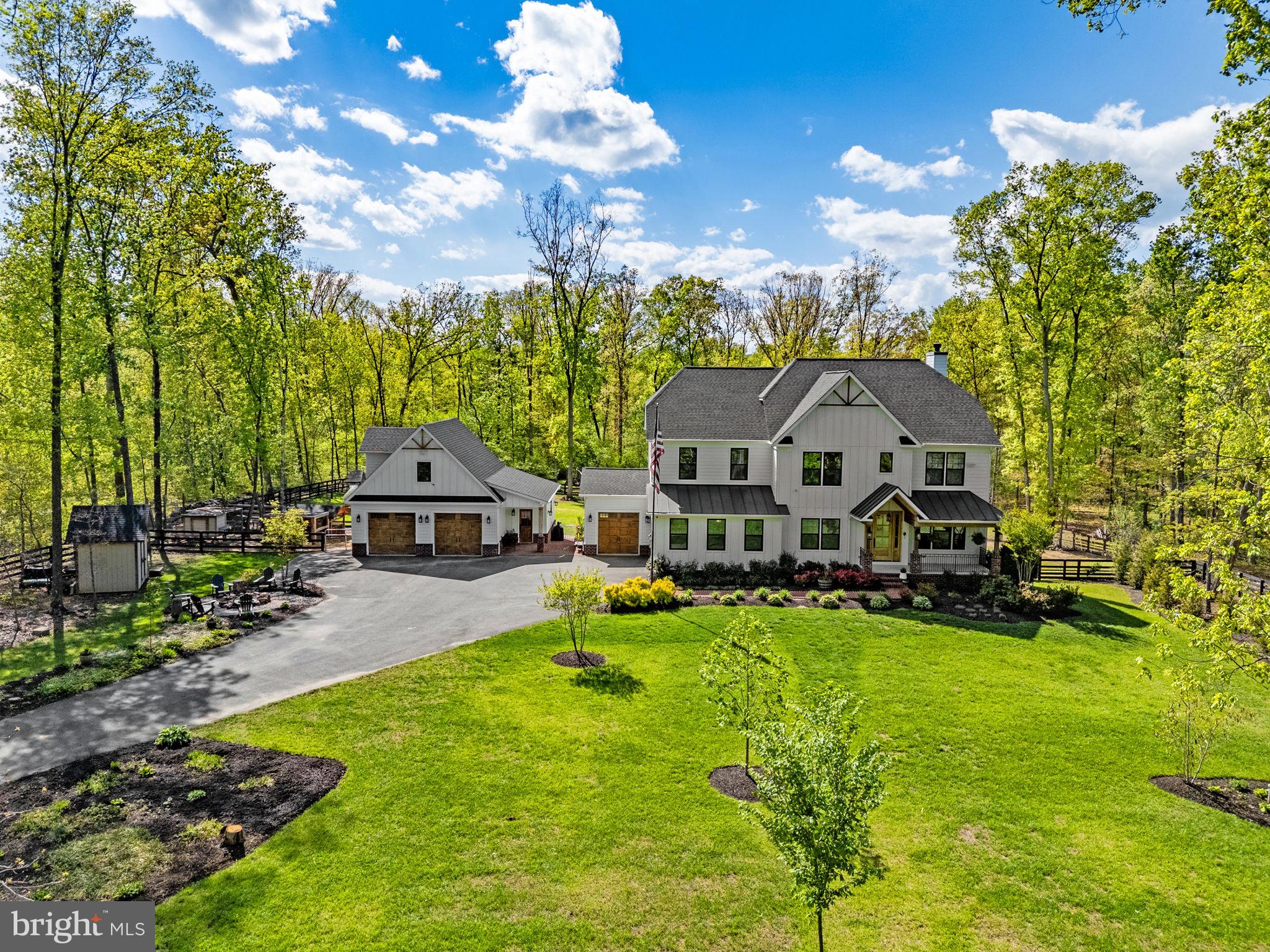 **Welcome to this stunning, nearly-new craftsman-style home nestled in the sought-after Buckland Woods area on 5 park like acres. Built in 2020, this beautifully appointed 7-bedroom, 6-bathroom residence spans over 6,000 square feet of thoughtfully designed living space — offering the perfect blend of modern elegance and everyday comfort.  Step inside to find custom features, sun-drenched interiors, and premium finishes throughout. The open-concept main level flows effortlessly from a chef's kitchen — complete with quartz countertops, stainless steel appliances, and a generous island — into a spacious great room ideal for entertaining.  A dedicated office nook, mud room with built in lockers & walk-in pantry are just a few of the  "extras" that make this home not only beautiful, but functional too!!  A main level en-suite bedroom is tucked away and perfect for guests.  Just off the dining area, you'll find a screened-in porch to take in the views.   Upstairs, retreat to a luxurious primary suite featuring a spa-inspired en-suite bath, walk-in closets & sitting area, accompanied by well-sized secondary bedrooms and additional full baths & laundry.  The finished lower level provides flexible space with rec room including wet bar, a media room, gym/bedroom & full bath.  Windows and doors let in ample natural light and allow easy access to patio & fenced yard.   With a 3 car attached garage, oversized detached garage/workshop with additional space above (could be easily finished), there is no shortage of storage or hobby space.  For hobby farmers, the chickens even have luxury accomodations and be sure to take advantage of the greenhouse.  Enjoy the tranquility of this peaceful, picturesque neighborhood surrounded by mature trees and the natural beauty of Western Prince William County. Located within walking distance to Lake Manassas, an easy drive to boutiques and dining of Haymarket, Gateway Shopping, Route 66, and Route 29.  This is Northern Virginia living at its finest — where privacy, style, and location converge. Don't miss your opportunity to call this exceptional property home.