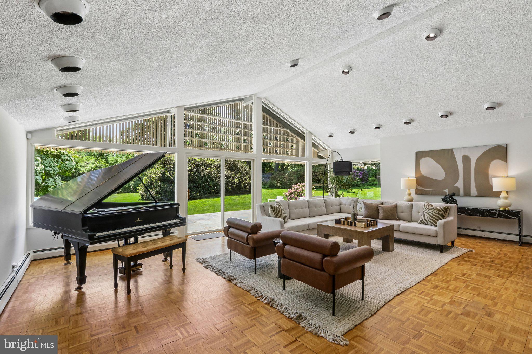 PRICE IMPROVEMENT! Introducing The Estate on Paper Mill, a rare private residence where architectural character, Mid-Century Modern influence, and resort-style living come together on 1.75 beautifully landscaped acres. Set in one of Meadowbrook’s most desirable locations, this distinctive 5-bedroom, 4.5-bath home offers over 4,800 square feet of living space, a saltwater pool, private tennis court, mature gardens, and exceptional indoor-outdoor living. 

A glass entry introduces the home’s striking personality and opens to a dramatic vaulted great room with soaring ceilings, a wall of windows, parquet wood floors, a gas-burning stone fireplace, wet bar, and direct access to a flagstone patio overlooking the private rear grounds. Thoughtfully oriented toward the backyard, the home is filled with natural light, garden views, and seamless access to outdoor living spaces.

The first-floor primary suite is a true retreat with serene views, a sitting room with built-in bookcases, walls of windows, multiple walk-in closets, and two separate baths. The formal dining room seats twelve and features a skylight, built-in china cabinetry, and generous storage.

The kitchen blends warmth, function, and professional-grade performance with white cabinetry, butcher block countertops, a large island with seating, vegetable sink, pantry, sitting area, window seat, and premium appliances including a 6-burner Wolf range, Sub-Zero refrigerator and freezer, Miele oven, and Bosch dishwasher. Direct access to the covered patio makes outdoor dining effortless.

Additional first-floor spaces include a family room with Amish-crafted built-in desks, a cubbied mudroom, and laundry room with Miele washer and dryer leading to a fenced vegetable garden. Upstairs, four additional bedrooms offer large windows, organized closets, and access to two full baths.

Beyond the heated two-car garage are rare bonus spaces including a bike room, workshop, garden room, and upstairs studio ideal for an office, fitness room, art space, or quiet retreat.

The grounds are the signature. Cultivated over decades, the property features mature trees, lush landscaping, flagstone paths, a fenced rear yard, saltwater pool redone in 2021, expansive lounging deck, storage/bar area, and views toward the private tennis court. Whether entertaining, swimming, playing tennis, gardening, or relaxing on the patio, this property offers a private resort lifestyle rarely found in Meadowbrook.

Additional amenities include a whole-house generator, drainage system, deer fencing, 5-zone heating and air, expanded circular driveway with carport, alarm system, tennis storage shed, and extensive storage throughout. Conveniently located near train lines to Center City, Pennypack trails, Huntingdon Valley Country Club, hospitals, and within the Abington School District.