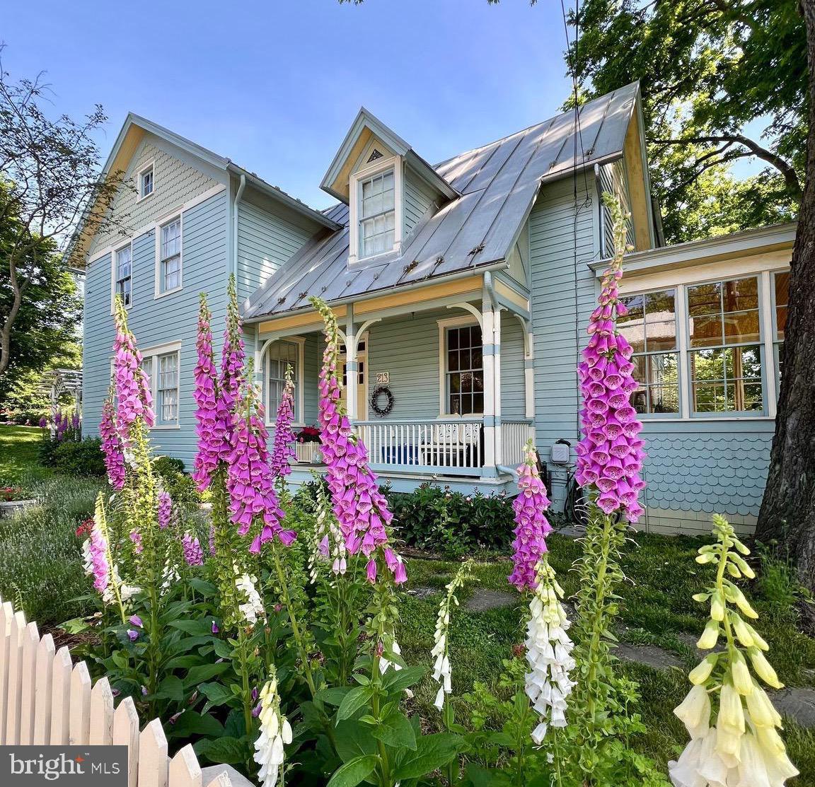 Welcome to 213 W High Street! This beautifully preserved 2-story residence rests on a DOUBLE, corner lot in the Historic District. The charming home showcases original architectural elements and offers the perfect balance of comfort, style, and history. Its plaster walls, wood floors and double-hung wood windows have been lovingly maintained. It exudes historical character as you enter through the original front door and into an open foyer with fireplace. A set of original glass paneled doors with transoms lead out to a light-filled sunroom with 12 original six-foot-tall windows! The wainscoting and pickled floorboards encompass this space. The formal dining room creates a gracious space for memorable meals and celebrations. Here a built-in custom bar coordinates with the original fireplace mantle trim while the original, diamond pattern lead glass windows create a distinctive focal point. The dual alcoves provide closet or hutch space. (This area could be renovated to a 1st floor bedroom as the adjacent half bath was once a full bath!) To the left of the entry an elegant, yet comfortable living room is flanked by a grand fireplace and floor to ceiling built-in bookcases. Music played from here can be piped to speakers around the main floor.  A standout feature in the kitchen is the custom-built cabinetry with abundant storage space, recycling center, kitchen desk, and display shelves which were all thoughtfully integrated. Beautiful schoolhouse lights were carefully repurposed from a local church remodel while the striking black and white tile floors add a bold, graphic touch. Kitchen finishes include stainless-steel appliances, Corian countertops, and a Kohler farmhouse sink. A powder room is tucked behind a discreet pocket door in the butler’s pantry.  An additional flex space lends itself to endless possibilities with floor to ceiling built-in shelves and wondrous natural light (office, guest room, playroom, craft room or even a small home business). The functional mudroom, with sizable utility closet, hosts a walk-in pet shower/cleaning room along with a second small stairway and a hidden cellar door. The rear screened porch leads to a lovely deck path where you will find your very own hidden spa with a hot tub, private changing area and outdoor shower! Adjacent is a custom stone patio with a thoughtfully arranged fire ring and planters that create a harmonious outdoor retreat! Upstairs, the four bedrooms boast historic charm with built-in shelves and aspects of the original fireplaces.  The soaking tub in the remodeled full bath is also original to the house. The primary bedroom is a cozy retreat with transom stained-glass art, leaded glass diamond window, an en suite primary bathroom and entry to the second floor sleeping porch. The stairway to the full-house attic is also located off of the sleeping porch. Followed by a cozy second floor TV room (or bedroom) with a built-in desk for homework or gaming! This space flows into the laundry room with separate Kohler deep utility sink and a unique ductless dryer. The next room is currently used as a home office, but could function as a bedroom or be converted back to a kitchenette space. Cabinets along one full wall once outfitted a sink & small fridge! Outside, immerse yourself in the enchanting gardens, where nature and history seamlessly intertwine.  The historic rock walls, meandering stone paths, and two custom-built sheds add charm, character as well as utility. The fenced vegetable garden is a true highlight, providing a protected space to grow fresh produce and herbs. The many species of native trees support birds & butterflies while shading the house in the heat of summer. Immerse yourself in the splendor of this historic, small town.  Conveniently stroll to the C&O Canal, restaurants, shops, or Shepherd University. Schedule a personal tour to explore this stunning piece of history! See listing documents for Final Plat of Lot A and Lot B to convey with this sale.