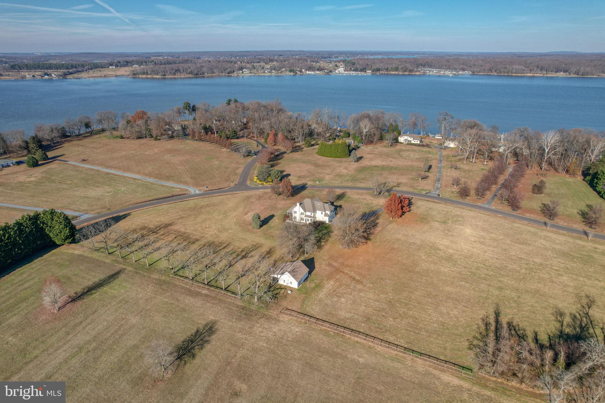 Escape to your own 16+ acre sanctuary where sweeping water views of the northern Chesapeake Bay and unforgettable sunsets are everyday living. Set in a unique community on the Bohemia River, this custom-built home is a true reflection of thoughtful design, meticulous care, and genuine pride of ownership. Tucked within a quiet, close-knit community of just 29 residences, this home was designed with careful attention given to every detail, from the layout and finishes to how the home captures natural light. Enhanced by private, groomed walking and riding trails that wind through the wooded surroundings and a park-like setting with a gazebo, it offers the perfect blend of refined living and outdoor freedom. The property also allows for up to two horses, a rare opportunity in a private community, lending itself to an elevated equestrian lifestyle. A welcoming 2-story foyer with ceramic tiles opens to gleaming hardwood floors that flow through the living room, dining room, and family room, where classic crown molding, chair rail, recessed lighting, and an abundance of windows create a warm atmosphere. The heart of the home is the large family room, anchored by a beautiful stone wood-burning fireplace and overlooking the surrounding acreage, while French doors lead to a screened porch with ceramic tile and recessed lighting - an ideal place to unwind and take in the peaceful views connecting to a wraparound deck also accessible from the breakfast room. The kitchen is functional and inviting, boasting granite countertops, cherry cabinetry, tile backsplash and ceramic flooring. Additional features include a walk-in pantry, double wall ovens, island prep sink, and spacious breakfast bar. A powder room is tucked just off the foyer. Upstairs, hardwood stairs and hallways lead to an expansive primary suite with a deep tray ceiling, hardwood floors, recessed lighting, windows on multiple sides, an en-suite bath with jetted tub, separate shower and water closet as well as an expansive walk-in closet. Three additional well-sized bedrooms, full bath, and large second-floor laundry room with utility sink provide everyday convenience. The full basement spans the entire footprint of the home and is accessible through the two-car turned garage, which also includes a powder room. Complementing the main residence is a versatile secondary structure featuring a well-equipped workshop with built-in dust collection and HEPA air filtration, ideal for woodworking, creative pursuits, or serious hobbies along with a barn-style storage area that includes additional storage. Perfectly poised for equestrian use, this building can easily be converted into a barn, or a new facility can be built for avid horse lovers. The property is vast and private, bordered by mature trees, woods, and water access. Outdoor enthusiasts will appreciate the landscape alive with natural beauty, including deer and bald eagles. Boating, fishing, and quiet exploration are all part of everyday life here. Horse enthusiasts can enjoy private trails right on the property itself with even more riding opportunities just minutes away, including Bohemia River State Park and Fair Hill Natural Resources Area, known for their expansive trails on thousands of scenic acres. This home has been exceptionally well cared for and is truly move-in ready, supported by a substantial recent investment of over $60K in professionally completed stucco remediation and exterior improvements, undertaken proactively to enhance longevity and peace of mind. Despite its peaceful, tucked-away setting, the property is well-connected with high-speed fiber optic internet and offers convenient access to Philadelphia, Baltimore, and private or regional air travel. Just minutes from Middletown, Delaware and Chesapeake City, you'll find wineries, shopping, and waterfront dining just a short drive away. Don't miss this rare opportunity to own a lovingly built and impeccably maintained Chesapeake Bay retreat. Welcome home!
