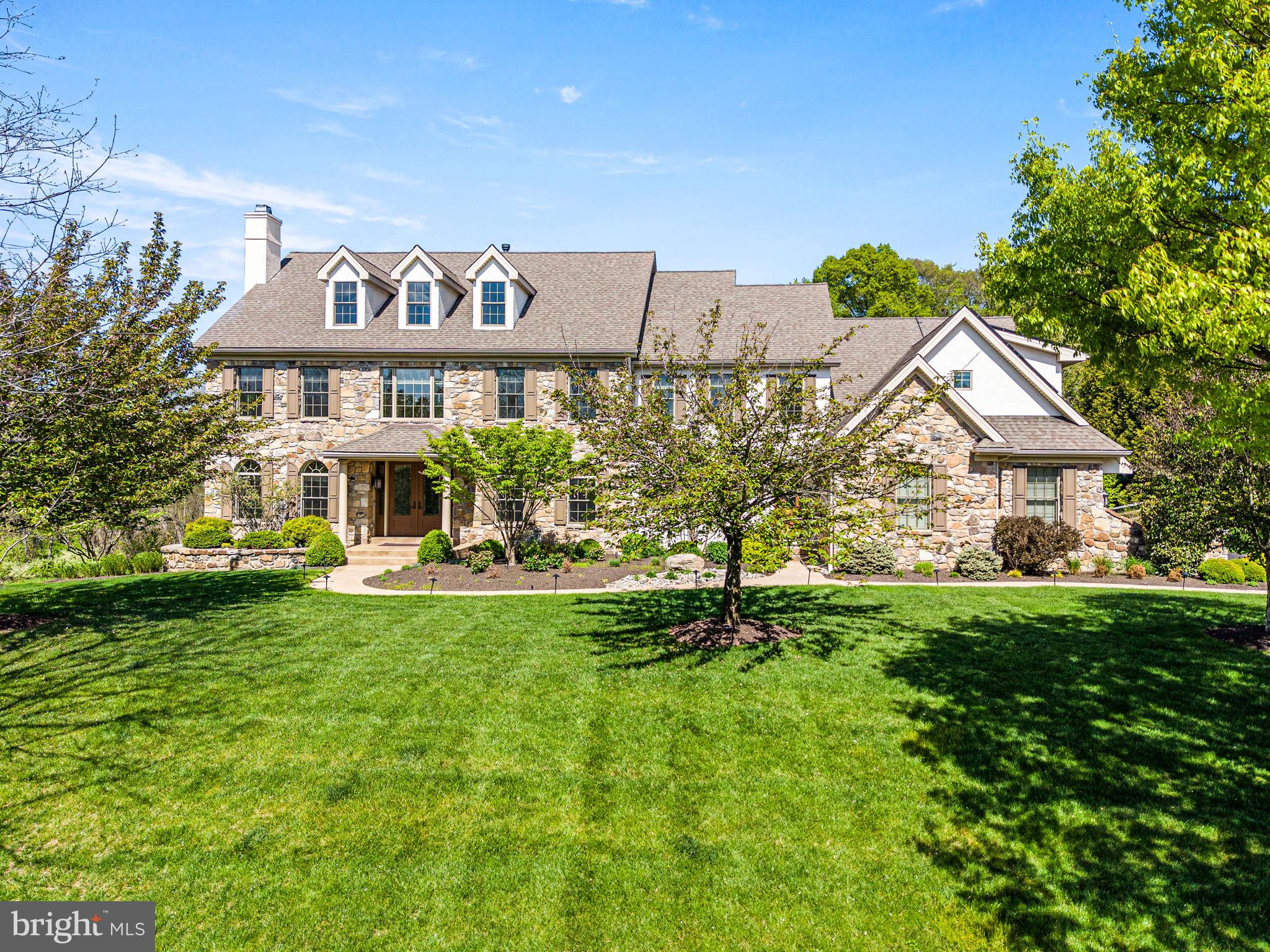 Welcome to this spectacular, impeccably maintained home situated on a premium lot in a most desirable neighborhood. Impressive curb appeal with professional landscaping and lighted walkway sets the tone for what awaits inside. Step through the front door and experience a refined, elegant interior filled with natural light streaming through expansive windows, highlighting rich hardwood floors and exquisite millwork. The sophisticated living room offers an inviting space to gather, complete with a gas fireplace featuring a stone surround and handsome woodwork. The generously sized formal dining room is ideal for both intimate dinners and larger celebrations and is complemented by a convenient butler’s pantry and wine refrigerator for seamless entertaining. The stunning, designer kitchen is truly a showpiece, featuring floor to ceiling walnut cabinetry, illuminated open shelving, and a striking glass wine closet with translucent quartzite. Crisp white cabinetry and quartz countertops add contrast, while the oversized island comfortably seats five. Premium appliances include separate Sub-Zero refrigerator and freezer units, two Bosch dishwashers, a Wolf double oven, a Wolf six burner cooktop with griddle, and a Wolf built in microwave. The bright breakfast room overlooks the picturesque backyard and opens to a spacious low maintenance deck, perfect for outdoor dining. The private backyard oasis showcases lush landscaping with blooming trees and shrubs, along with a heated, salt water pool featuring a waterfall, lighting, and expansive flagstone patio and decking. Adjacent to the kitchen, the large family room features a wood burning fireplace with an impressive surround and a wall of windows that brings the outdoors in. The main level also includes a spacious office with custom built ins, a light-filled sunroom, a mudroom with built-in cubbies, and two half baths. Upstairs, the primary suite offers a private retreat with sitting room, gas fireplace, and built in cabinetry, along with two large custom closets and a luxurious bath with dual vanities and soaking tub. Two guest bedrooms feature en-suite baths, while two additional bedrooms share a Jack and Jill bath. A large laundry room with abundant storage completes this level. The finished walk-out lower level is equally impressive, boasting a large recreation/game space with gas fireplace and a granite bar equipped with refrigerator, dishwasher, and microwave. The media room is designed for entertainment with projector, screen, surround sound, and leather power recliner seating. This level also includes a guest room, two full baths, a gym area, and generous storage space. Additional features include a whole house generator, solar panels (owned and transfer with property), two electric vehicle chargers, water filtration system, irrigation system, and landscape lighting. Situated in the highly sought-after Unionville-Chadds Ford School District, minutes from West Chester Borough and Longwood Gardens, with easy access to major routes, shopping, and dining. Truly an extraordinary, move-in ready home just waiting for its lucky new owners!