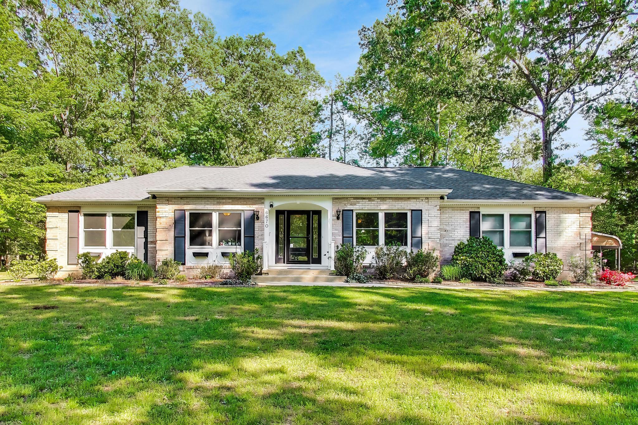Contract pending release - Updated all-brick rambler on nearly 1 acre! This 3BR, 2BA home offers an open layout with a spacious living/dining area featuring a brick wood-burning/gas fireplace. Kitchen includes 42” cabinets, stainless steel appliances, smooth-top range, convection oven, under-cabinet lighting, dual sink & breakfast bar, and open to the main living space. Bright sunroom overlooks a private, partially wooded rear yard. Flexible room with chair railing, currently used as a 4th bedroom (ideal for an office/den or formal dining room). Primary suite includes a walk-in closet & an updated ensuite bath. Both bathrooms have been recently renovated.  Laundry/mudroom off kitchen leads to side-load 2-car garage and access to rear yard. Exterior features new vinyl fencing w/ 3 gates, patio, large shed & additional 2+ car carport. Home sits well off the street for added privacy. Upgrades include hardwood floors, ceramic tile, ceiling fans throughout, a new 25-year roof & Andersen Low-E sunroom windows (transferable warranties), double-hung windows & gutter guards. Heat pump w/ oil backup. Convenient to schools, shopping & parks—peaceful setting!