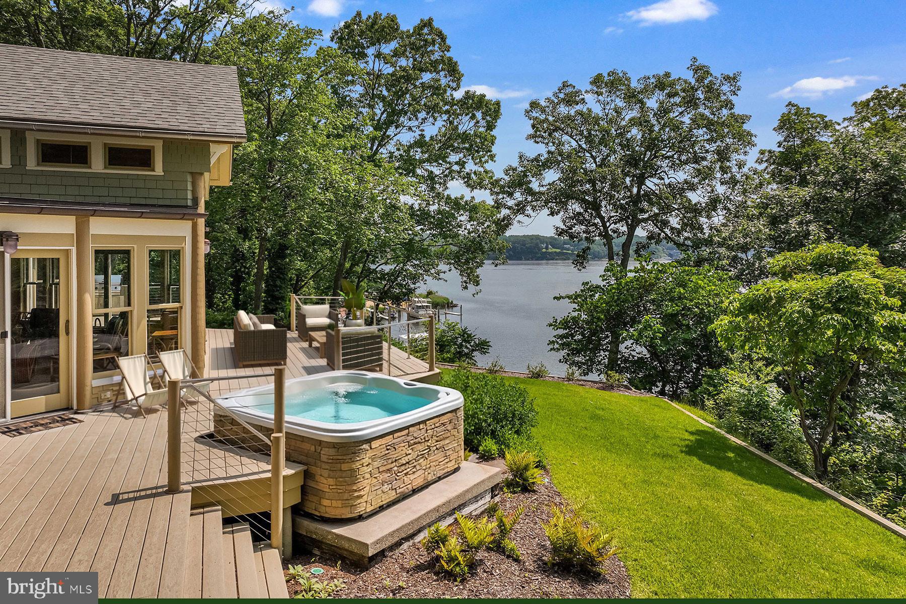Ideally situated on the banks of Luce Creek with sweeping views down the Severn River, 1715 Porters Hill Road is a unique heritage property with over a century of history. Set on a 1.7 acre lot with 265 ft of waterfrontage, the property includes a large, hard-to-find boathouse that provides both charm and utility for all your waterfront adventures. The private pier has 7+ ft water depth and can accommodate a large vessel as well as an assortment of smaller boats. The tram makes access to the water effortless, and the entire property enjoys an exceptional privacy.
Steeped in its storied past yet thoughtfully updated for modern living, this retreat captures the perfect balance of historic charm and casual elegance. The heart of the home is a sunlit great room with original log walls and quarried stone fireplace, a vaulted ceiling, and expansive windows which frame water views at every turn. An adjoining den, with separate entrance option, is a perfect place to relax. This could easily become another main level bedroom with ensuite bathroom. The kitchen is striking under its vaulted ceiling accented by exposed beams. The custom cabinetry, GE Monogram stainless steel appliances and generous island give the space so much functionality while maintaining the artisanal character. The kitchen opens to the dining area overlooking the water. The table is anchored by a craftsman-style light fixture, and the entire first and second floors have beautiful wood floors. Step outside and you’re embraced by nature: multiple porches and decks overlook lush, manicured grounds that lead down to the water’s edge. 
The main-level primary suite is a true sanctuary, designed for privacy and tranquility. The bedroom, with a vaulted ceiling, has a screened porch overlooking the water. Two expansive walk-in closets offer custom organization systems that would make a clothing connoisseur smile.  The spa-like bathroom gets lots of natural light from the windows that frame the water, and the freestanding soaking tub is situated to enjoy this view. A dual-sink vanity, heated floors, generous walk-in shower with a built-in bench, and a spacious cosmetic area with dedicated seating make getting ready feel effortless and luxurious. A dedicated laundry area just off the hallway makes day-to-day living very easy. Part of the primary suite is a gracious office with gas fireplace and outdoor access. This is a totally flexible space: install a wall of bookshelves and you’d have a lovely library.
Upstairs, there are two generously sized bedrooms. One has water views and a waterside balcony; the other overlooks the lush landscaping out front. There is a hall bathroom.  A separate guest bedroom suite above the garage, complete with its own living area and luxe bathroom, is ideal for visiting friends and family who desire more privacy.  The Historical Context: Originally built in the 1880s, this log house was one of three identical structures used as hunting lodges. It is the only one that remains. The construction of the log house is one of great craftmanship, including sizing each log to be approximately the same diameter as others. Lore has it that around the turn of the 20th century, the Naval academy wanted to acquire more land by the academy and traded this peninsula for land across from College Creek. The Naval Academy superintendent, Admiral David Porter, could be where the name Porter’s Hill derived from. In the 1920’s, the Whitehead family – three brothers known for running bootleg liquor to Baltimore and Washington during Prohibition — used the property as a place to entertain and stop on the way to Baltimore. In the 1940s, the brothers’ exploits caught up with them, and the State of Maryland confiscated the Porters Hill peninsula. Through a unique trade involving the Jones family’s gravel pit (now the site of the 895 Tunnel), this private waterfront enclave found its next chapter.