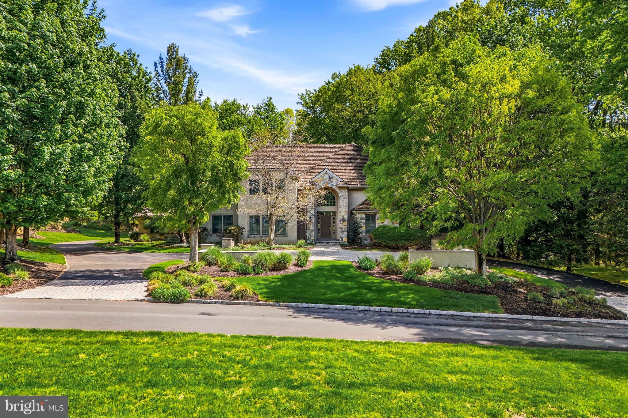 Welcome to 7 Mercer Gate Drive, a stately and elegant estate home, custom-built by its discerning owner and set on a private, 1+ acre property in desirable Doylestown Township. This exceptional residence offers 4/5 bedrooms, 5 full baths, and 1 half bath, including a convenient main-level guest suite. Nestled on a wooded cul-de-sac lot adjacent to a tranquil pond, the home enjoys a serene, nature-filled setting while remaining just minutes from all that Doylestown Borough has to offer.
A dramatic two-story foyer with a Palladian window welcomes you inside, complemented by radiant heated flooring throughout, custom trim work, moldings, wainscoting, and shadow boxing that extend across much of the home. Thoughtfully designed living spaces feature high ceilings, recessed lighting, plantation shutters, and timeless architectural details, blending elegance with everyday comfort across 5,322 square feet of living space.
At the heart of the home is the impressive great room, framed by arched doorways with custom trim and built-ins that connect the main entertaining areas. A gas fireplace serves as the focal point, creating a warm and inviting gathering space.
The adjacent kitchen is beautifully appointed with granite countertops, a built-in refrigerator, double wall ovens, microwave, dishwasher, gas cooktop, and an expansive walk-in pantry. A center island with seating and a peninsula provide both function and gathering space, while abundant cabinetry, including glass-front display cabinets, offers excellent storage and style. The sun-filled breakfast room overlooks the rear yard and provides access to the maintenance-free wrap around Trex deck.
A formal dining room with additional built-ins offers an elegant setting for entertaining, while the living room features a bar area and connects to an oversized sunroom with French doors leading to the deck. The main level also includes a private den or office, a guest bedroom suite with a full bath, a powder room, and a spacious mudroom with access to the four-car garage.
Two staircases, one off the foyer and one off the kitchen, provide convenient access to the second level. Upstairs, the luxurious primary suite features double-door entry, a dressing room, en-suite bath, and two organized walk-in closets. The primary bath includes vaulted ceilings, heated floors, a large walk-in shower with glass block accents, jetted jacuzzi whirlpool tub, double vanity, private water closet, and additional linen storage. Two additional bedrooms with walk-in closets and en-suite baths, a large den with triple window, a spacious laundry room with cabinetry and walkup stairs to a large floored attic, complete the second floor.
The finished lower level provides an additional 1,795 square feet of living space with 10-foot ceilings. This level offers exceptional flexibility with a large entertainment room and a separate versatile space ideal for a gym, office, or hobby room. A private, versatile room featuring a full bath and walk-in closet offers additional living space, perfect for live-in support. The remaining portion of the basement is unfinished with a full door egress, balancing function and storage.
Additional highlights include a security system, surround sound, central vacuum, four-zone air conditioning, eight-zone radiant gas heating, walk-up attic storage, and a circular drive with ample parking.
Located in the Central Bucks School District and just minutes from Doylestown’s shopping, dining, parks, and cultural attractions, this home offers the perfect balance of luxury, comfort, privacy, and convenience.