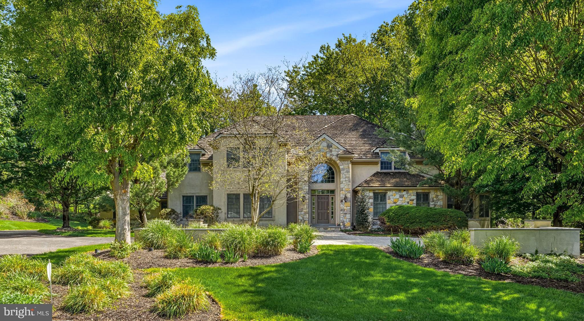 Welcome to 7 Mercer Gate Drive, a stately and elegant estate home, custom-built by its discerning owner and set on a private, 1+ acre property in desirable Doylestown Township. This exceptional residence offers 4/5 bedrooms, 5 full baths, and 1 half bath, including a convenient main-level guest suite. Nestled on a wooded cul-de-sac lot adjacent to a tranquil pond, the home enjoys a serene, nature-filled setting while remaining just minutes from all that Doylestown Borough has to offer.
A dramatic two-story foyer with a Palladian window welcomes you inside, complemented by radiant heated flooring throughout, custom trim work, moldings, wainscoting, and shadow boxing that extend across much of the home. Thoughtfully designed living spaces feature high ceilings, recessed lighting, plantation shutters, and timeless architectural details, blending elegance with everyday comfort across 5,322 square feet of living space.
At the heart of the home is the impressive great room, framed by arched doorways with custom trim and built-ins that connect the main entertaining areas. A gas fireplace serves as the focal point, creating a warm and inviting gathering space.
The adjacent kitchen is beautifully appointed with granite countertops, a built-in refrigerator, double wall ovens, microwave, dishwasher, gas cooktop, and an expansive walk-in pantry. A center island with seating and a peninsula provide both function and gathering space, while abundant cabinetry, including glass-front display cabinets, offers excellent storage and style. The sun-filled breakfast room overlooks the rear yard and provides access to the maintenance-free wrap around Trex deck.
A formal dining room with additional built-ins offers an elegant setting for entertaining, while the living room features a bar area and connects to an oversized sunroom with French doors leading to the deck. The main level also includes a private den or office, a guest bedroom suite with a full bath, a powder room, and a spacious mudroom with access to the four-car garage.
Two staircases, one off the foyer and one off the kitchen, provide convenient access to the second level. Upstairs, the luxurious primary suite features double-door entry, a dressing room, en-suite bath, and two organized walk-in closets. The primary bath includes vaulted ceilings, heated floors, a large walk-in shower with glass block accents, jetted jacuzzi whirlpool tub, double vanity, private water closet, and additional linen storage. Two additional bedrooms with walk-in closets and en-suite baths, a large den with triple window, a spacious laundry room with cabinetry and walkup stairs to a large floored attic, complete the second floor.
The finished lower level provides an additional 1,795 square feet of living space with 10-foot ceilings. This level offers exceptional flexibility with a large entertainment room and a separate versatile space ideal for a gym, office, or hobby room. A private, versatile room featuring a full bath and walk-in closet offers additional living space, perfect for live-in support. The remaining portion of the basement is unfinished with a full door egress, balancing function and storage.
Additional highlights include a security system, surround sound, central vacuum, four-zone air conditioning, eight-zone radiant gas heating, walk-up attic storage, and a circular drive with ample parking.
Located in the Central Bucks School District and just minutes from Doylestown’s shopping, dining, parks, and cultural attractions, this home offers the perfect balance of luxury, comfort, privacy, and convenience.