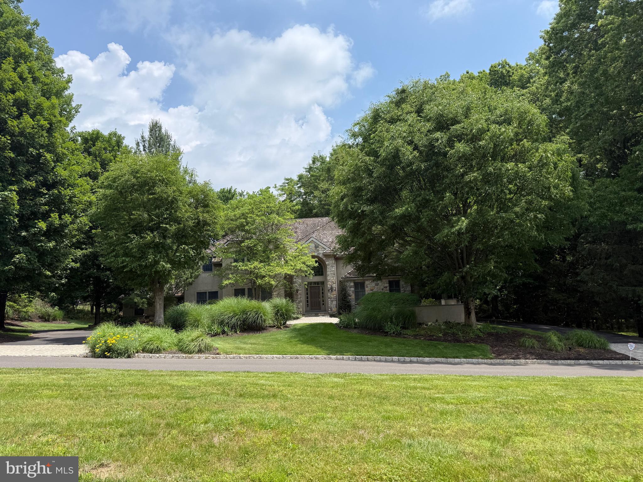 Welcome to 7 Mercer Gate Drive, a stately and elegant estate home, custom-built by its discerning owner and set on a private, 1+ acre property in desirable Doylestown Township. This exceptional residence offers 4/5 bedrooms, 5 full baths, and 1 half bath, including a convenient main-level guest suite. Nestled on a wooded cul-de-sac lot adjacent to a tranquil pond, the home enjoys a serene, nature-filled setting while remaining just minutes from all that Doylestown Borough has to offer.
A dramatic two-story foyer with a Palladian window welcomes you inside, complemented by radiant heated flooring throughout, custom trim work, moldings, wainscoting, and shadow boxing that extend across much of the home. Thoughtfully designed living spaces feature high ceilings, recessed lighting, plantation shutters, and timeless architectural details, blending elegance with everyday comfort across 5,322 square feet of living space.
At the heart of the home is the impressive great room, framed by arched doorways with custom trim and built-ins that connect the main entertaining areas. A gas fireplace serves as the focal point, creating a warm and inviting gathering space.
The adjacent kitchen is beautifully appointed with granite countertops, a built-in refrigerator, double wall ovens, microwave, dishwasher, gas cooktop, and an expansive walk-in pantry. A center island with seating and a peninsula provide both function and gathering space, while abundant cabinetry, including glass-front display cabinets, offers excellent storage and style. The sun-filled breakfast room overlooks the rear yard and provides access to the maintenance-free wrap around Trex deck.
A formal dining room with additional built-ins offers an elegant setting for entertaining, while the living room features a bar area and connects to an oversized sunroom with French doors leading to the deck. The main level also includes a private den or office, a guest bedroom suite with a full bath, a powder room, and a spacious mudroom with access to the four-car garage.
Two staircases, one off the foyer and one off the kitchen, provide convenient access to the second level. Upstairs, the luxurious primary suite features double-door entry, a dressing room, en-suite bath, and two organized walk-in closets. The primary bath includes vaulted ceilings, heated floors, a large walk-in shower with glass block accents, jetted jacuzzi whirlpool tub, double vanity, private water closet, and additional linen storage. Two additional bedrooms with walk-in closets and en-suite baths, a large den with triple window, a spacious laundry room with cabinetry and walkup stairs to a large floored attic, complete the second floor.
The finished lower level provides an additional 1,795 square feet of living space with 10-foot ceilings. This level offers exceptional flexibility with a large entertainment room and a separate versatile space ideal for a gym, office, or hobby room. A private, versatile room featuring a full bath and walk-in closet offers additional living space, perfect for live-in support. The remaining portion of the basement is unfinished with a full door egress, balancing function and storage.
Additional highlights include a security system, surround sound, central vacuum, four-zone air conditioning, eight-zone radiant gas heating, walk-up attic storage, and a circular drive with ample parking.
Located in the Central Bucks School District and just minutes from Doylestown’s shopping, dining, parks, and cultural attractions, this home offers the perfect balance of luxury, comfort, privacy, and convenience.