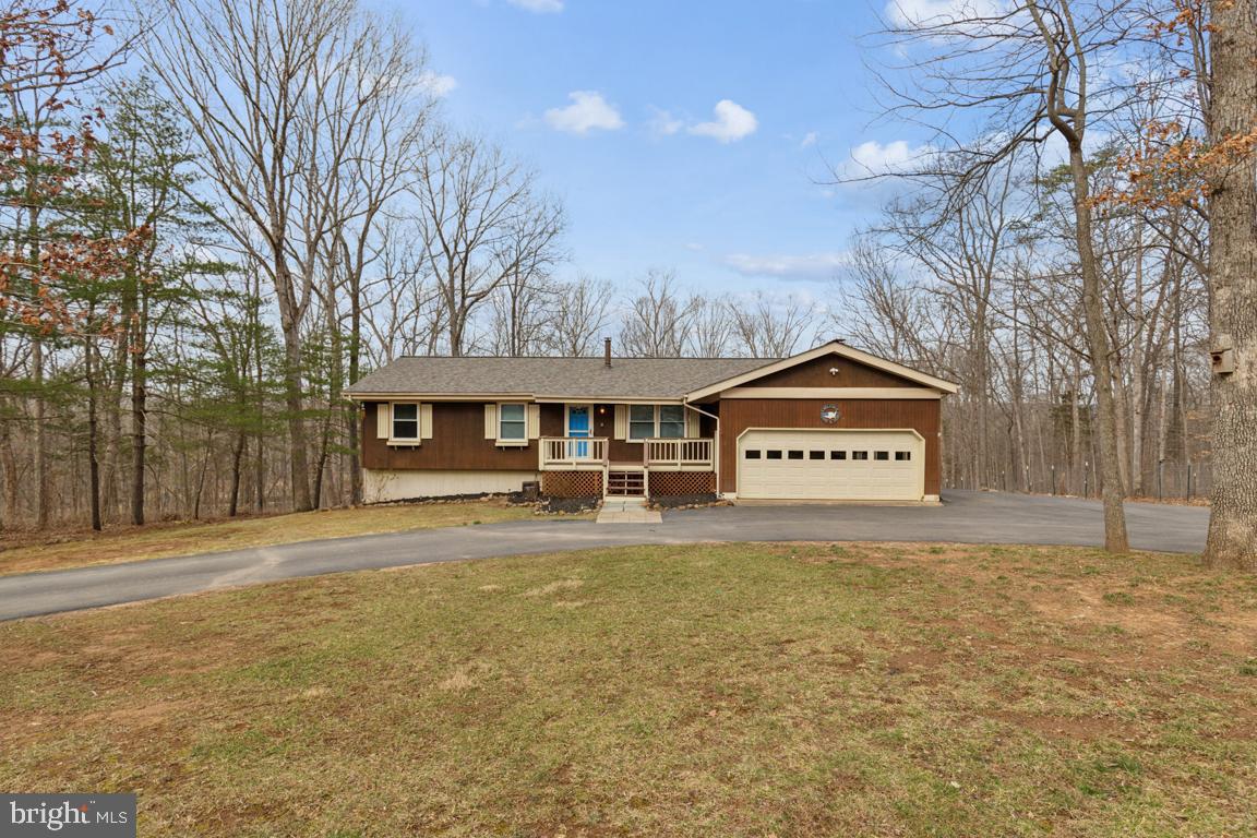 This light and bright five-bedroom three full bath rambler is nestled down in a private cul-de-sac on a one-and-a-half-acre wooded lot. This meticulously maintained home boasts a brand-new roof, fresh paint throughout and gleaming hardwood floors, creating an inviting atmosphere from the moment you step inside. The open-concept main level features a bright living room, dining area with custom chandelier and French doors to the rear deck and a modern kitchen with ceramic tile flooring, island bar seating with pendant lighting and Samsung stainless-steel appliances. Cozy up by the woodburning stove in the family room with large picture window overlooking the wooded rear yard or retreat to the primary suite with its gleaming hardwood floors and en-suite bath. Entertain effortlessly on the expansive front and rear decks and patios or around the fire pit in the side-yard graveled area.  The walk-out lower level is complete with recreation room, laundry, two additional bedrooms and a full hall bath. A horseshoe driveway, parking pad and attached two-car garage provide excellent parking for family and friends and the side-yard fenced coop offers the delightful opportunity to raise chickens for fresh eggs daily or the ability to house your choice of small livestock, be it goats or pigs. This home provides the perfect blend of comfort, privacy and outdoor living in a serene neighborhood setting!