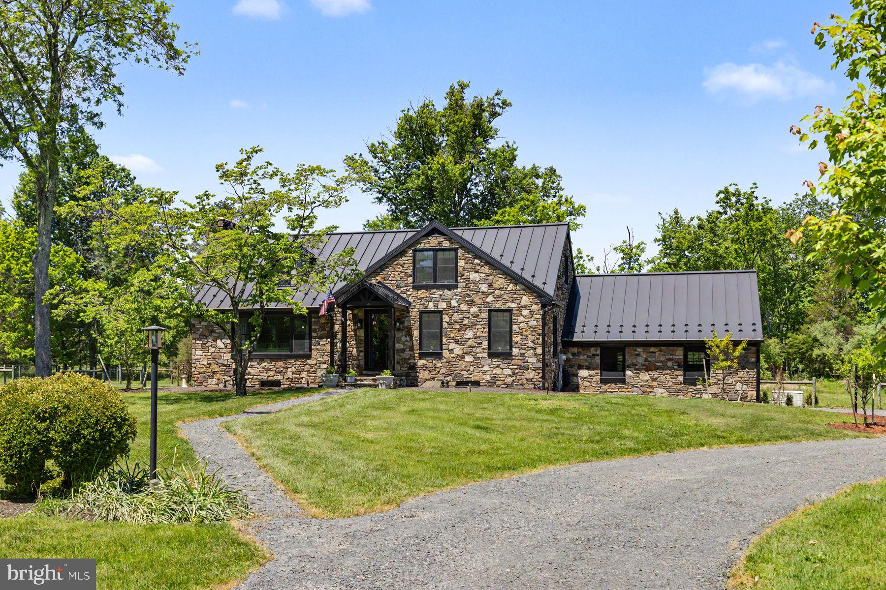 Set on 6 peaceful, lush acres in Upper Bucks County, Country Cottage is a rare jewel box offering a beautifully balanced blend of charm, comfort, and thoughtful modern updates. Surrounded by wide-open fields, mature trees, and established gardens, this stone colonial, built in 1956, has been extensively renovated and is truly move-in ready.
Inside, a welcoming foyer opens to a sun-filled living room featuring refinished hardwood floors and the home’s original 1956 stone, wood-burning fireplace, a warm and timeless focal point. Natural light pours in through expansive windows, creating an inviting and airy atmosphere throughout the main living spaces. The living room flows seamlessly into a formal dining room with views of the expansive backyard, ideal for both everyday living and entertaining.
The newly renovated kitchen is a standout, complete with crisp white cabinetry, stainless steel appliances, new countertops, and a large sink window overlooking the serene grounds. The first floor also includes two comfortable bedrooms and a beautifully remodeled full bath.
Upstairs, the home continues to impress with three additional bedrooms, all featuring original hardwood flooring and abundant natural light. Next to the primary bedroom is a charming sitting room, perfect for a private retreat, reading nook, or home office. A second newly remodeled full bathroom completes the upper level.
Significant recent upgrades include a new metal roof, Pella windows throughout, and updated heating and air conditioning, ensuring comfort and peace of mind for years to come. The unfinished lower level connects directly to the 2-car garage, offering a laundry area, additional storage, and functional space.
Outdoors, the property is thoughtfully designed for both relaxation and gardening, offering a true extension of the home’s peaceful country setting. The fenced backyard includes a shed for convenient storage, while a separate fenced garden provides ample space to grow whatever you desire, from vegetables and herbs to flowers and fruit. Mature trees and open green space create a serene backdrop, inviting quiet mornings, outdoor gatherings, or simply enjoying the natural surroundings in privacy.
Country Cottage is a rare opportunity to enjoy refined country living, peaceful, private, and beautifully updated, while still remaining conveniently close to major commuter routes and all of the wonderful shops and restaurants of New Hope.