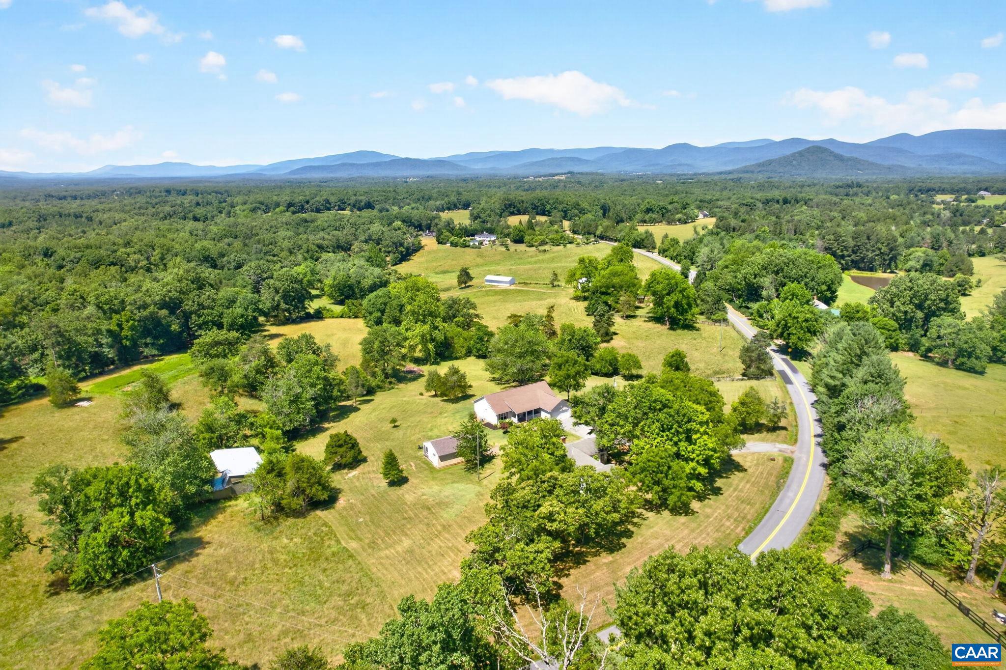 Nestled on 4 private acres in the heart of Earlysville, this beautifully maintained one-level home offers stunning winter mountain views, 3 bedrooms, and a dedicated home office. A welcoming covered front porch leads into an open floor plan featuring hardwood floors, a spacious living room with a gas fireplace, and an eat-in kitchen with white cabinetry, stainless steel appliances, a custom butcher block island, custom lighting, and access to the rear deck for effortless grilling and entertaining. The split-bedroom design provides privacy, with the primary suite tucked away from the secondary bedrooms. It features a large walk-in closet and an en suite bath with dual vanities and a tiled walk-in shower. Two additional bedrooms are generously sized and share a full bath. Outside, enjoy the best of country living with room to roam, a classic tree swing, an attached two-car garage, and an impressive 768-square-foot detached garage/workshop?ideal for hobbies, storage, or a home business. An additional outbuilding offers endless potential to restore as a guest cottage, studio, or possible income-producing space. All of this is just minutes from shopping while offering the peace, privacy, and space you've been searching for.,Granite Counter,White Cabinets,Wood Counter,Fireplace in Living Room