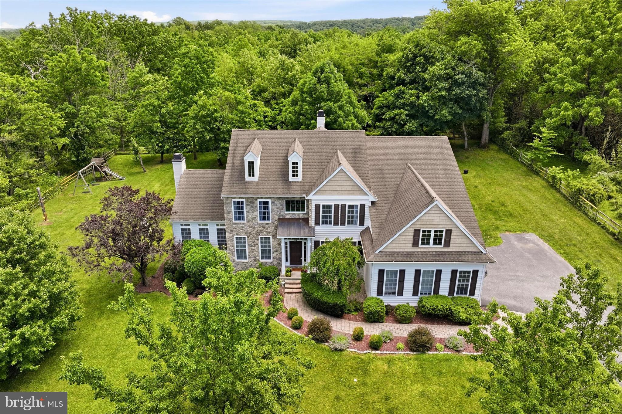 Set well back from the road on 1.36 private acres in sought-after Charlestown Township, this custom-built residence offers the rare combination of privacy, flexibility, and convenience. Located within the Great Valley School District, the property enjoys a peaceful setting adjacent to a permanently preserved 10+ acre property protected by conservation easement, while remaining just minutes from the charm of downtown Phoenixville shopping and dining.

A fenced-in rear yard opens to a wooded backdrop with informal walking trails enjoyed by nearby residents, and a gate provides direct access from the property. Whether hosting gatherings, enjoying time with pets, or simply relaxing outdoors, the setting offers an attractive combination of privacy and usable outdoor space. Charlestown Township Park, with walking trails, playgrounds, and ballfields, is just a short walk away.

Inside, thoughtful design and quality craftsmanship are evident throughout. The heart of the home is a gourmet kitchen featuring a center island, breakfast area, 6-burner range, pot filler, and seamless flow into the dramatic two-story family room highlighted by an oversized floor-to-ceiling stone wood-burning fireplace. Formal living and dining rooms provide excellent entertaining space, while pocket doors open to a sun-filled conservatory with walls of windows, fireplace and wet bar. A private main-floor study with built-in bookshelves, mudroom with built-in lockers, and dual staircases complete the main level.  You'll appreciate the custom millwork throughout much of the main level.

Upstairs, a loft overlooking the family room offers the perfect space for a reading nook, homework station, play area, or second office. The spacious primary suite features a luxurious bath with dual vanities, soaking tub, and stall shower, along with an expansive custom dressing room complete with a center storage island and extensive built-in cabinetry. A separate laundry room conveniently located off the primary suite enhances everyday living.

The finished walkout lower level offers exceptional flexibility with a full bath, a sizeable second home office, exercise area, potential guest or fifth bedroom space, and a custom home theater featuring a projection system, screen, speakers, and media equipment that will remain with the home.

Outdoor living is equally impressive with an expansive deck, paver patio, firepit gathering area, and peaceful views of the surrounding landscape.

Additional features include a 3-car garage, built-in Sonos audio system, tankless water heater, generator hookup, whole house surge protection and public sewer.

A rare opportunity to own a custom Chester County home that offers room to gather, room to work, room to play, and room to unwind, all just minutes from the vibrant energy of Phoenixville Borough.