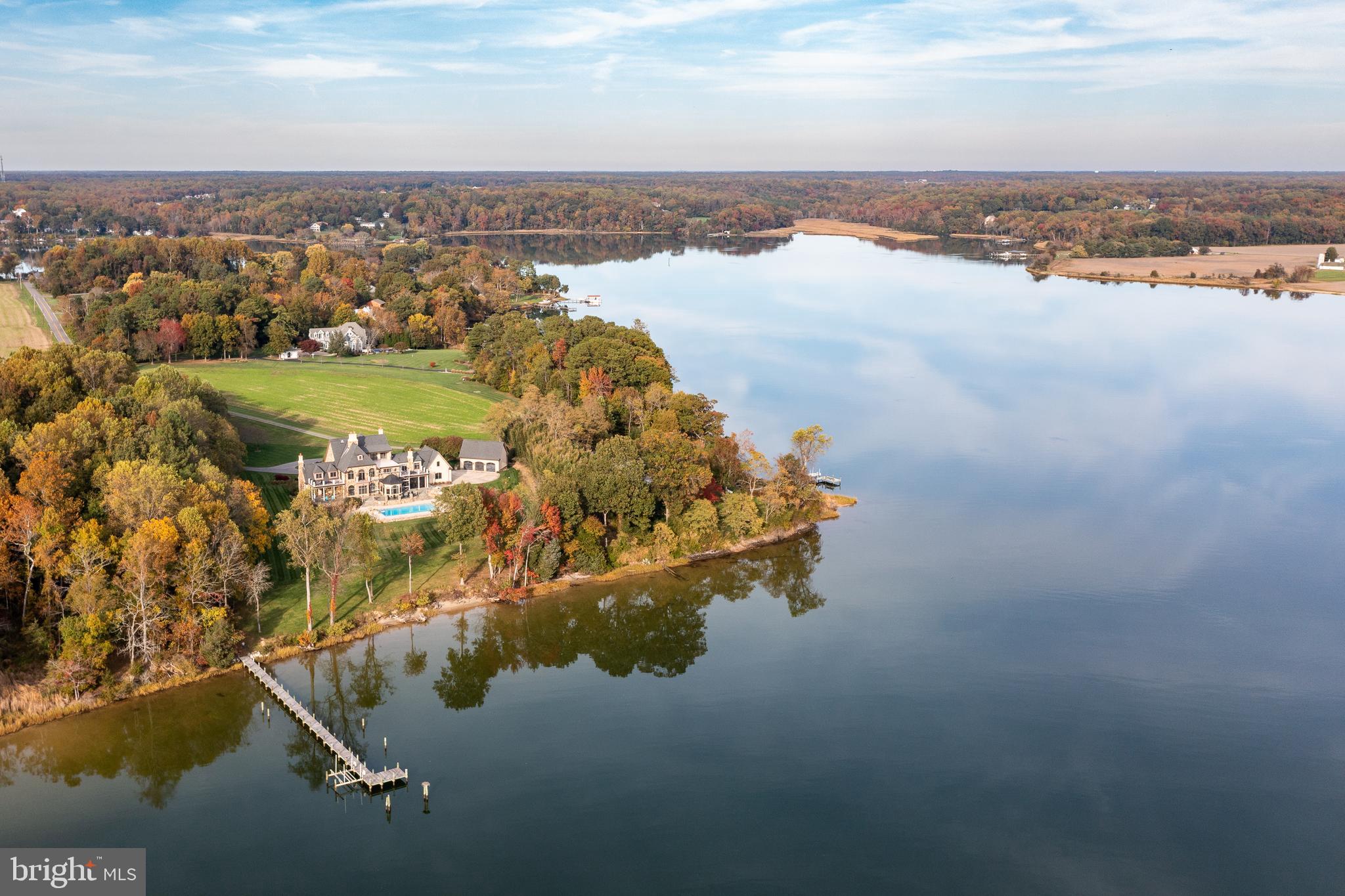 Stunning. Welcome to a world of unparalleled luxury and breathtaking beauty. Nestled along the tranquil waters off of the Potomac River, this custom-built four level waterfront estate on almost 18 acres, is a testament to architectural brilliance and sophisticated design. 
As you approach the grand entrance, you are greeted by a circular driveway, detached 3-car garage, attached 2-car garage, lush landscaping and a sense of serenity. Step inside and you'll be captivated by the focal point of the home, a striking spiral staircase that ascends to the four levels, adding a touch of drama and splendor. A private elevator also awaits to effortlessly transport you through each level of this palatial residence. The expansive living space is adorned with floor-to-ceiling windows, offering panoramic views of the shimmering waters that stretch beyond the horizon. The soul of this home is undoubtedly the gourmet kitchen, a culinary masterpiece featuring top-of-the-line appliances, custom cabinetry, a massive center island and a breakfast room with a groin vault ceiling that doubles as a gathering place for friends and family. Enjoy seamless indoor-outdoor living with access to an expansive terrace with retractable screens, perfect for al fresco dining or simply soaking in the astounding landscape. The flawless design of the main level seamlessly connects the formal living, dining, main living, full bathroom, butler’s pantry, study, half bathroom, additional office, laundry room, mudroom and kitchen areas, creating an atmosphere of effortless grandeur. One of the standout features of this estate is the luxurious study, a haven for those seeking a refined space for work or contemplation. The custom-built cabinetry, rich wood paneling, and expansive views create an atmosphere of insight and productivity. As you ascend the spiral staircase within it, you'll discover an additional upstairs library space and doors that connect to the primary suite that redefines luxury living. Wake up to wondrous views of the water, and unwind in the evenings in a recently renovated spa-like en-suite bathroom complete with a soaking tub and a walk-in steam shower that can reach 105 degrees. The primary suite also boasts a private terrace overlooking the pool, creating a serene sanctuary within your own home. The walk-in closet is a haven for the fashion connoisseur, providing two wings with ample space for two curated wardrobes. As you continue on the second level, discover additional well-appointed bedrooms, each with its own en-suite bathroom.  The fourth level offers a luxurious guest suite with its own bathroom fully handicapped accessible, a wet bar and a rooftop terrace commanding awe-inspiring views of the surrounding waters, creating an unrivaled setting for sunset cocktails or stargazing. The lower level is a crowning jewel, featuring a generous and versatile space that unveils a recreation area, guest or au pair suite, and a vast amount of storage.  The outdoor living space is a true oasis, featuring a sparkling saltwater pool that seems to merge seamlessly with the grounds and bay beyond. There is an inground timed sprinkler system providing a green and luscious lawn year round. The pier has been resurfaced and the mean low water is 8 feet, ensuring that priceless maritime adventures begin just steps from your doorstep. In the sought after Leonardtown school district, the property possesses a Silver Leed certification and can withstand a Category 3 hurricane with a reinforced roof. While you will feel miles away from it all, you will be enamored by the charm, history and convenience of the area. DC is 90 minutes away, St. Mary’s Airport is 20 minutes away and a five minute boat ride to the wharf and lovely downtown Leonardtown. The Breton Bay Country Club is just two miles away or visit nearby Solomons Island, the Patuxent Naval Air Station or enjoy a quick kayak ride to a nearby winery or a summer sea plane ride. Welcome home.