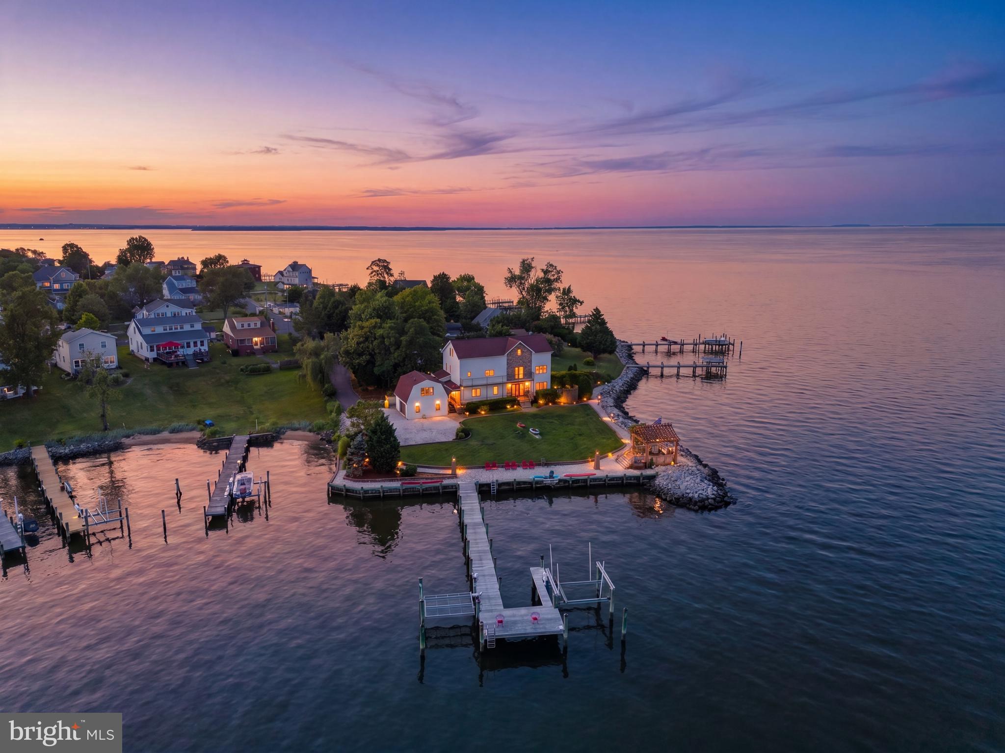 This idyllic waterfront estate offers a unique blend of luxury and nature, perfect for those seeking a serene retreat. Nestled on two combined lots (Lot 24 and Lot 25), this energy-efficient concrete home combines superior construction with modern elegance. Featuring 4 bedrooms, 3.5 baths, a 2-car garage with an apartment suite, and 360 feet of waterfront with a stunning 270-degree panoramic view of Chesapeake Bay and Bodkin Creek, this property exudes both colonial charm and contemporary design.

Upon entering the foyer, you'll be greeted by designer lighting, pocket doors, in-floor heating, European tilt-and-turn windows, tray ceilings, and high-quality hardwood floors. The home is adorned with elegant granite windowsills and includes a laundry room, zoned heating, and central air.

The gourmet kitchen is a chef's dream, boasting custom-made cherry cabinets with bird's eye maple inlays, granite countertops, a wine cooler, an oversized glass cooktop stove, a double oven, and a large pantry with a second refrigerator. The open and airy living room features a granite gas fireplace and ample space for gatherings, all with commanding views.

The second-floor master suite offers a sitting area with a morning bar, a private balcony, a large spa tub, a glass block shower, marble countertops, and glass sinks. The third floor includes a library or private home office with a custom wrought iron railing, a wood beam ceiling, and wood windowsills.

The property is beautifully landscaped with two gardens, expansive grass areas with an automatic watering system, and a charming large oak gazebo illuminated with soft lights and a maintenance-free floor, accessible via a gravel path from the house. The Brazilian oak pier features sturdy pilings with copper protective caps, two boat lifts (7,000 and 8,000 pounds), and slips for boats with up to four feet of draft. 

Conveniently located between Baltimore and Annapolis, it provides easy access to Alexandria, VA, Washington, D.C., and Potomac, Bethesda…MD—all within an hour's drive. The water is perfect for all kinds of activities, including boating, kayaking, and paddleboarding. 

This waterfront retreat seamlessly combines comfort, style, and functionality, making it a must-see for those seeking luxury living in a picturesque setting.