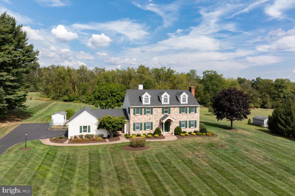 Built in 1971 by renowned local builder Bill Calhoun of Calhoun Builders, this five-bedroom, three-and-a-half bath home carries the timeless character, thoughtful design, and quality workmanship that Calhoun homes have been known for across generations. From the street, the home makes a commanding yet welcoming impression. Its stately stone façade, accented with crisp siding, green shutters, and three dormered windows along the roofline, embodies balance and tradition. The arched entry and brick chimney add warmth, while the sweeping lawn creates a sense of grandeur. For 51 years, the same family has lovingly cared for this home… celebrating holidays in the expansive dining room, gathering for summer afternoons by the pool, and filling its rooms with the milestones of family life. Offered now for the first time in more than half a century, the property reflects a lifetime of care and devotion. While the home is move-in ready, its next chapter invites the vision of new stewards… those who will appreciate its craftsmanship and history, while also embracing the opportunity to make it their own through thoughtful updates. Set on 2.3 acres along one of the area’s most desirable little-traveled roads, the property offers both serenity and accessibility. Just minutes from the heart of Doylestown the New Hope/Lambertville river towns and with excellent access to major routes, it combines privacy you want with the convenience you need. This is more than a house… it’s a tradition, a legacy, and an opportunity to continue the story of a beloved Bucks County home.
Inside, thoughtful details and practical upgrades abound. A bonus room opens to a generous 14’ x 32’ three-season porch, the perfect spot for relaxing or entertaining. The home offers two fireplaces for cozy evenings, along with a coveted cedar closet and the convenience of central vacuum. Comfort is assured year-round with two-zone heating, a whole-house fan, and the best of both worlds: oil radiator heat paired with central air conditioning.  The side-turned 2 car garage is handily oversized.. Modern systems include a 220-amp electrical service, newer vinyl siding and replacement  Anderson windows (2004), and a newer roof (2019). Outdoors, the property shines with an in-ground heated Norris pool (propane), an 8’ x 16’ storage shed, and landscaped grounds designed for both play and retreat.
Come see for yourself, fall in love with its timeless charm, and imagine the memories you’ll create here. Opportunity knocks! Don’t miss your chance to make this beloved Bucks County home your own and continue its story for generations to come.