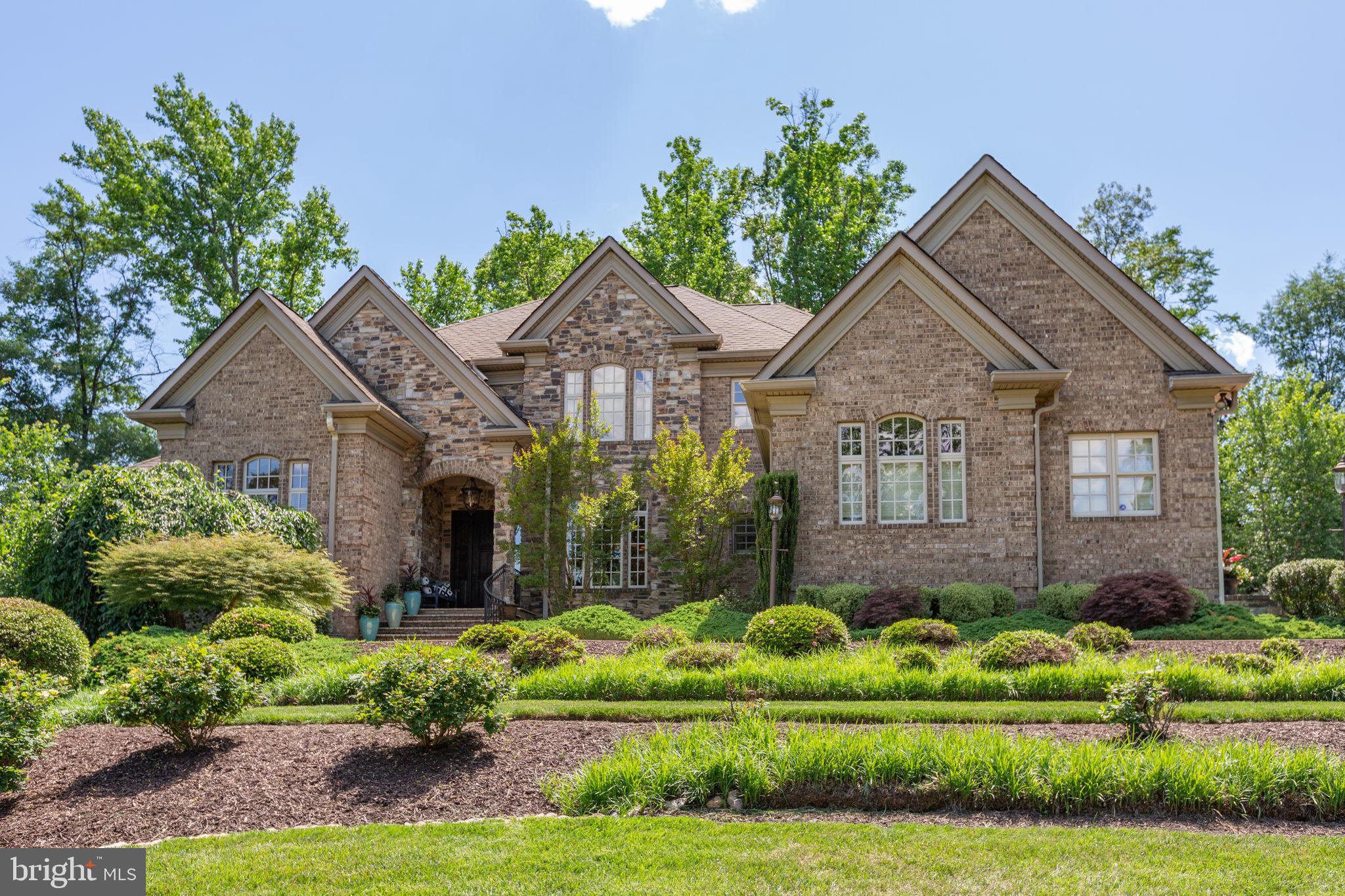Welcome to 6 Delahay Drive, an extraordinary custom estate built in 2007 by renowned builder Dallas Barnes of Stonehaven Homes. The stately brick exterior with stone entryway creates an unforgettable first impression.  Step inside the dramatic two-story foyer featuring a spectacular curved walnut staircase, an electronically lowering chandelier for easy cleaning, and rich walnut hardwood flooring. The foyer opens to an elegant formal dining room and a private office with French doors and a coffered ceiling. Beyond, the breathtaking two-story living room showcases coffered ceilings, built-in bookcases flanking a marble gas-burning fireplace, and a wall of oversized Palladian windows overlooking the private backyard. This impressive room can also be viewed from the second-story overlook above. Designed for entertaining, the gourmet kitchen is a chef's dream and includes built-in speakers, featuring a granite island with a secondary copper prep sink, ice maker, warming drawer, custom glass backsplash, professional-grade Wolf six-burner gas range with professional hood, double wall ovens, Sub-Zero refrigerator, abundant custom cabinetry, and expansive workspace. The adjoining family room offers a cozy wood-burning fireplace and quaint cantilevered balcony, while the adjoining sunroom showcases beautiful natural wood and stone accents and offers direct access to the slate patio. The luxurious main-level primary suite offers a spacious sitting room, tray ceiling with custom uplighting, built-in speakers, and an incredible spa bath featuring heated natural travertine flooring, double vanity, and a custom glass steam shower with rain head, multiple shower heads, and body sprayers. A powder room and main-level laundry complete the first floor. Upstairs offers three spacious bedrooms, each with a private ensuite bath and granite countertops. One features a tub/shower combination, while the other two feature tiled walk-in showers with built-in benches and frameless glass doors. The custom finishes were chosen with a decorator's eye. The walk-out lower level includes a spacious recreation and game room, fitness room with commercial rubber flooring and built-in speakers. More gathering space includes a kitchenette with cherry cabinetry, granite countertops, sink, refrigerator, and dishwasher, plus an additional full bath for a post-workout hot shower . This level offers the perfect escape! Outdoor living is equally impressive with a slate patio, fire pit, and an outdoor kitchen featuring granite countertops, a premium Lynx grill with rotisserie, two-burner cooktop, built-in counters, and stainless counter-mounted drink chest. The professionally designed grounds feature mature landscaping and beautiful slate and limestone retaining walls. These have been relocated from a historic property, creating a truly distinctive setting. The custom details inside and out are truly remarkable. Additional highlights include two fireplaces, three-zone HVAC with separate systems for each level, tankless water heater, and exceptional craftsmanship throughout. This residence offers over 6,190 finished sq. ft. plus 1,183 unfinished sqft on a beautifully landscaped .5-acre cul-de-sac lot. The stamped concrete driveway provides ample guest parking and leads to a spacious four-car side-load garage with two double doors. Every detail has been thoughtfully designed to create a home of timeless elegance, luxury, and comfort that is truly one of the area's finest custom residences. This location is perfectly situated to be convenient to shopping, downtown restaurants, riverfront park, Mary Washington Hospital, and the commuter train. Come visit and start imagining your life on Delahay Drive.