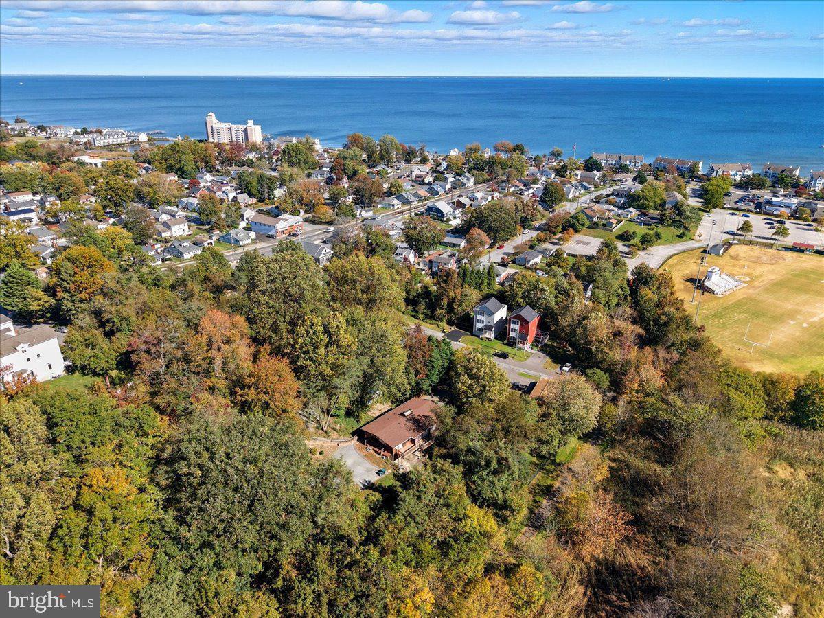 Architecturally distinctive and thoughtfully designed, this exceptional Acorn Deck Home offers a rare opportunity to own one of the area's most celebrated post-and-beam residences. Located in the heart of Chesapeake Beach, 8205 F Street showcases the timeless craftsmanship and design principles Acorn Deck Homes are known for—soaring ceilings, warm natural materials, dramatic walls of glass, and seamless connections between indoor and outdoor living. Expansive windows and sliding patio doors fill the home with natural light while framing beautiful outdoor views from nearly every room. The main level features a spacious great room anchored by a fireplace, a formal dining room, and a fully equipped kitchen designed for everyday living and entertaining. Two generously sized bedrooms and two full baths provide comfortable accommodations, while the screened porch and expansive decks on two sides of the home create inviting spaces to relax, dine, and enjoy the surrounding natural setting.The finished lower level offers exceptional flexibility with a second great room featuring a fireplace, a third bedroom, third full bath, laundry room, and utility room. Additional decking extends the living space outdoors, making this level ideal for guests, multi-generational living, or recreation. Recent improvements provide peace of mind, including a 50-year architectural roof installed in 2021, replacement of both heat pump systems in 2025, and new deck boards on both the upper and lower decks in 2025.bTwo separate driveways provide abundant parking, making this home perfectly suited for hosting family and friends. With Chesapeake Beach's renowned Fourth of July celebration just around the corner, there's still time to purchase, settle, and enjoy spectacular fireworks displays from the comfort of your own deck. This is more than a home—it's a unique architectural retreat designed to embrace light, nature, and the relaxed Chesapeake Beach lifestyle.