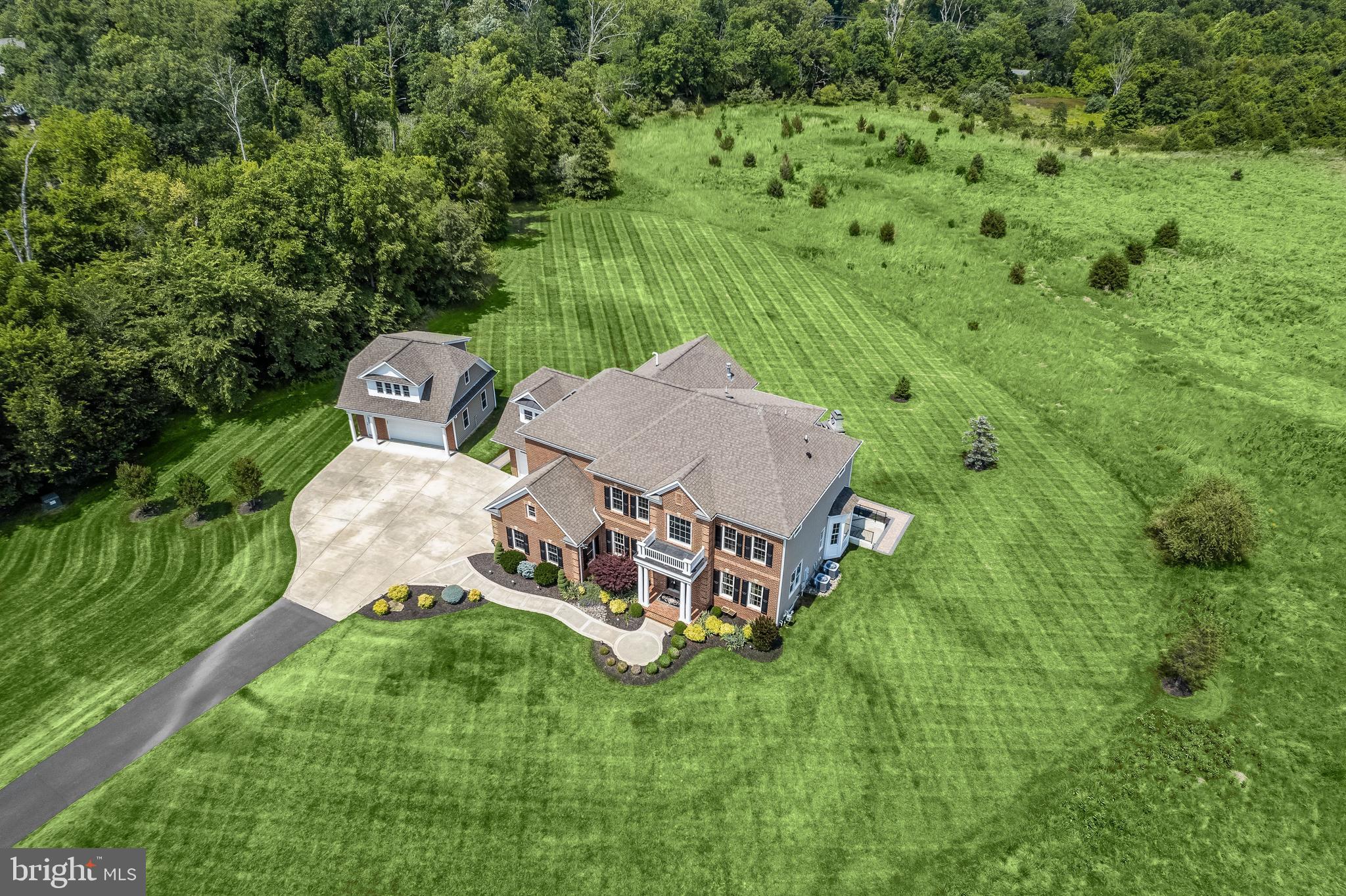 A truly  rare opportunity in Leesburg, VA with 32 rolling acres, a glistening pond, and a gorgeous residence located just minutes from parks, hiking, wineries, breweries, farms, shopping, entertainment, hip restaurants, and great schools. The HOA allows the property to add barns, stables & guest house. A quintessential board fence and a pair of stone pillars are capped with lantern lighting and announce entry to a private drive that leads to this very special property.  There is abundant parking, and a secondary entry allows quick access through the mud room outfitted with arrival cubby storage, bench, and closet.  From the outside portico, an eight-foot door with leaded glass sidelights will draw guests into a dramatic two-story entry foyer and open stair that is embellished with iron balusters, accent panel moldings, and multi-piece crown moldings.  Pristine finishes and hardwood floors are a unifying element throughout the main level beginning with living and dining formals that flank the entry foyer with generous openings, engaged columns, and wainscoting.  The open plan design seamlessly unfolds from the foyer into the central family room defined by a grand coffered ceiling and a gas fireplace with a striking hearth and stone surround on the main axis.   Quality woodwork, meticulous details, and fine finishes are standard throughout this impeccable home. The spacious kitchen is adjacent to the family room and is separated by a half wall and engaged columns that are repeated from the living and dining rooms. It is encircled by the back stair, mud room, laundry center, breakfast room, and dining patio. A commanding island and cook station with a designer pendant is open to the sink peninsula that overlooks the breakfast room and large windows that frame panoramic views of the grounds and trees beyond the expansive paver dining patio, outdoor fireplace, center fire pit and garden bench walls. Completing the main level is a private study enclosed with glazed French doors, and wrapped in windows that also frame views of the same panoramic vista.  Upstairs, the main house offers an extraordinary primary owner’s suite that includes a light-filled sitting room outfitted with a gas fireplace, wet bar, and beverage center on one side, and an atrium door to a private balcony on the opposite side.  The primary bath offers an extended double vanity with a white stone top, furniture-styled bun feet, and a soaking tub with a white marble surround.  Adjacent to the tub is an oversized walk-in shower with designer tile, body sprays, a handheld spray, and a shower with remote control on the wall. The owner’s suite bath leads into a two-room walk-in closet that will generously accommodate two wardrobes and a dressing area bathed in light from a daylight window. The upper-level sleeping quarters total five bedrooms including two ensuite bedrooms and two additional bedrooms with a shared Jack and Jill bath.  Downstairs, a fully finished lower level offers daylight from a pair of double atrium doors from the side lawn, leading into a recreation room, and billiards area, a full wet bar with a built-in, lighted back bar, and media niche, an exercise room, storage room, and fifth ensuite bedroom, attached full bath and linen closet.  The main house has two attached garages with three bays. One garage opens on two sides to accommodate tractor equipment. A detached garage offers two additional bays and a private entrance to the second-floor guest carriage house above.  The guest suite is equipped with a light-filled living room, dining room, kitchenette, and full bath, all meticulously finished with the same level of quality as is standard for this immaculate residence. Every detail, large and small in this premiere property has been carefully curated and maintained with the utmost care.  Come home to a like-new residence with plenty of room to live, work, play, and grow on 32 beautiful acres!