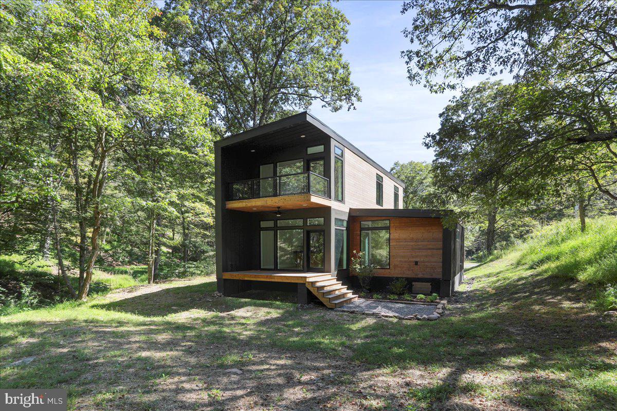 BRAND NEW CONSTRUCTION | Modern 3-Bedroom, 3-Bath Woodland Retreat | Price Improvement  Now Offered at $579,000       Step into this sleek, modern sanctuary tucked among the trees. This brand-new 3-bedroom, 3-bath home sits on nearly two private, wooded acres, offering a rare combination of contemporary design and immersive natural beauty. A serene stream-fed swimming hole sits along the edge of the property, and the Lost River State Park trail system — including new mountain biking trails — is located directly across the street.  Inside, the home is filled with light and views. Expansive Pella windows and glass doors create walls of glass throughout the open kitchen, dining, and living areas, framing the forest and gentle stream below. The sights and sounds of nature: flowing water and rustling leaves set a peaceful backdrop for daily living.  The home features modern architecture paired with quality finishes, including quartz countertops, custom cabinetry with floating shelves, and ducted central heating and air. Practical details make this home truly move-in ready: fiber optic internet, a private well with filtration system, brand-new Electrolux washer and dryer, and professional landscaping and hardscaping already in place. Two additional bedrooms offer privacy for guests and flexibility for a dedicated home office. Three porches extend the living space outdoors, ideal for entertaining or relaxing in nature.  The primary suite is a true retreat, featuring a private balcony overlooking the stream and waterfall, perfect for morning coffee, quiet reflection, or simply soaking in the stillness. This property would make an excellent short-term rental, while also being perfectly suited as a full-time residence or weekend escape, this is an  opportunity to enjoy modern living surrounded by nature, with easy access to hiking, biking, swimming, local markets, restaurants, boutique shops, and entertainment. Skip the build — this brand-new, move-in ready home lets you start mountain living immediately.  🎥 Be sure to click the video link and explore the interactive virtual tour, showcasing recent staging and offering two full video walk-through experience.