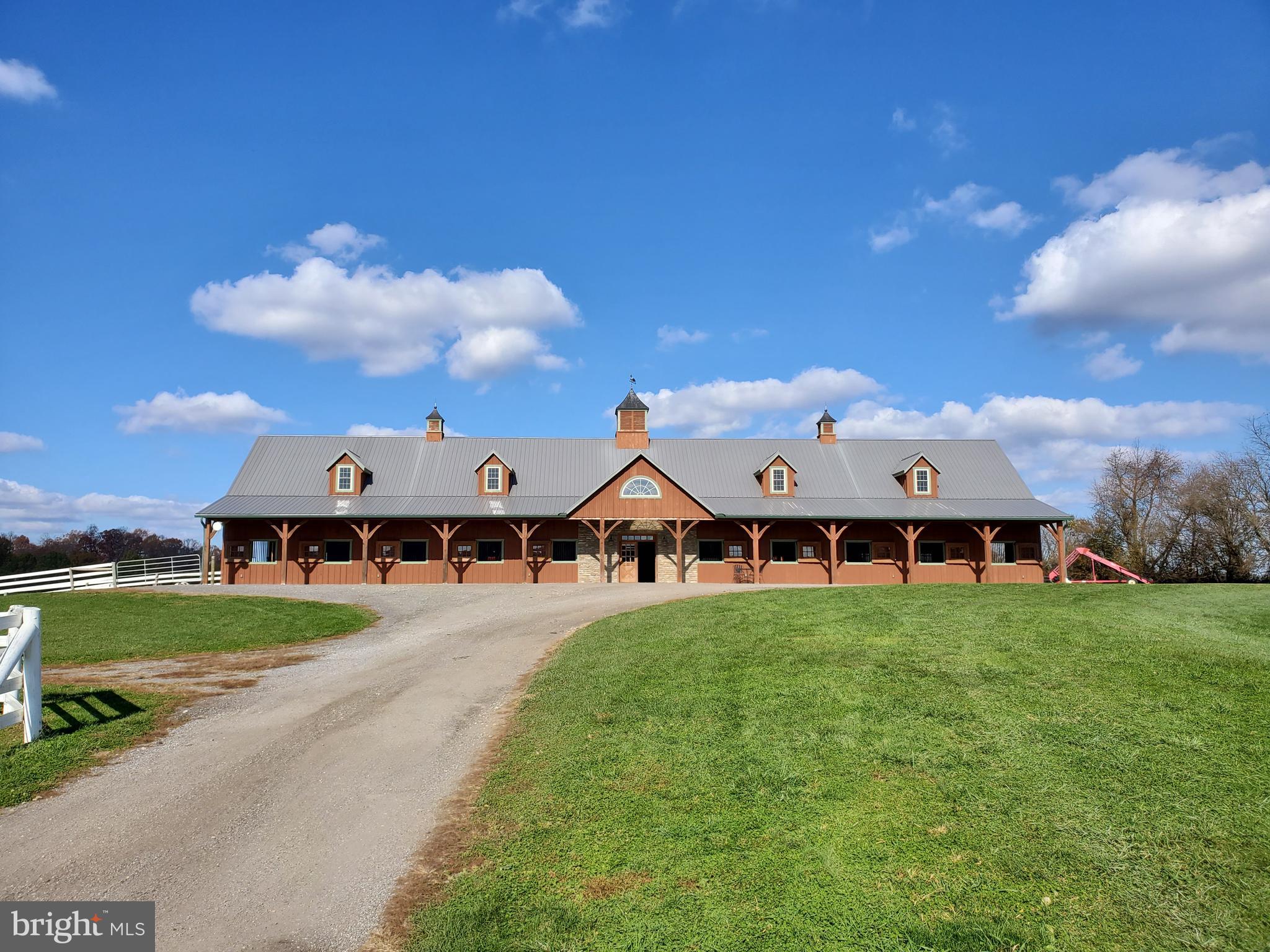 *** This is the Equestrian Training Center of Your Dreams! *** Look No Further!  Do you dream of training horses, teaching lessons, offering top caliber sales horses, or incomparable boarding services in the heart of Howard County?  Do you want a custom built barn with a state of the art indoor and custom footing?  Ready to take your competition horses to the next level with space for a large cross country course and full outdoor jump ring?  This farm is an incredibly successful boarding business for good reason.  Every element of this facility has been carefully curated to offer you, your horses and your clients the utmost in care, comfort, and amenities.  The farm offers 60 acres, 26 stalls, indoor and outdoor arenas, and an adorable updated farmhouse along with second homesite ready for your architect's designs.  The Main Barn set atop the hill offers thirteen stalls, a large nonslip aisle way with cathedral ceilings, thirteen matted stalls with removable yoke stall fronts, a tack room with custom lockers, and a climate controlled viewing lounge.  The viewing lounge is the perfect respite for your clients to review training videos, plan their competition year, or connect with each other over coffee.  The lounge offers a full viewing gallery with direct views of the state of the art indoor, a half bath, custom wet bar with full refrigerator, and a laundry closet.  Imagine hosting international clinicians here and inviting your guests to a catered lunch.  This spaces will make everyone feel welcomed and at home.  The indoor features sliding windows and four large doorways flooding the space with ventilation and daylight which makes it both reassuring and safe for your top horses.  The footing is a blend of stonedust and sand and the LED lights mean riding after dark is possible with minimal shadows.    For those clients wanting a more boutique setting, there is a seven stall barn as well.  This barn also offers a center aisle construction with nonslip rubber aisleway, large 12 x 12 stalls with water access to each stall, and large tack room with custom lockers for each horse.  There is also an external matted wash rack with cross ties and access to private pastures for ease of turnout.  Keep this barn or rent it out for additional income!    Additionally, there are two more shedrow barns on the property.  The four stall shed row features its own tack/feed room and each stall is matted with Nelson waterers.  There is access to private turnout pastures and these stalls can be opened to allow for them to serve as run-in sheds for horses wanting a bit more freedom of choice.  There is a two stall shed row with its own water, feed room, and electric which is connected to two large pastures.  The variety of barns on this property allows for many different boarding options and price points which can suit a variety of client preferences.    The large outdoor arena offers lights, custom blended stonedust footing, a full jump course, and safe Ramm fencing surrounding it.  Considering offering horse shows or clinics at your farm?  This ring could serve as an ideal showring or warmup space!  The arena has been perfectly graded and drains incredibly well. No more cancelled lessons or afternoons spent waiting for the ring to dry here.  The arena is just a short walk from all of the barns.  There are a variety of turnout options at the farm as well designed to support the needs of those requiring constant turnout to those horses who benefit from quiet time in a smaller private paddock.  Each paddock has access to water whether a frost free hydrant or automatic waterer and most fields have run-in sheds.  Each pasture is surrounded by safe Ramm fencing so you will no longer spend your precious free time replacing dangerous broken fence boards.    The updated two bedroom one bath farmhouse completes the farm AND there is one homesite available to build your dream home!  Buyer to complete perc.   Shown By Appt!