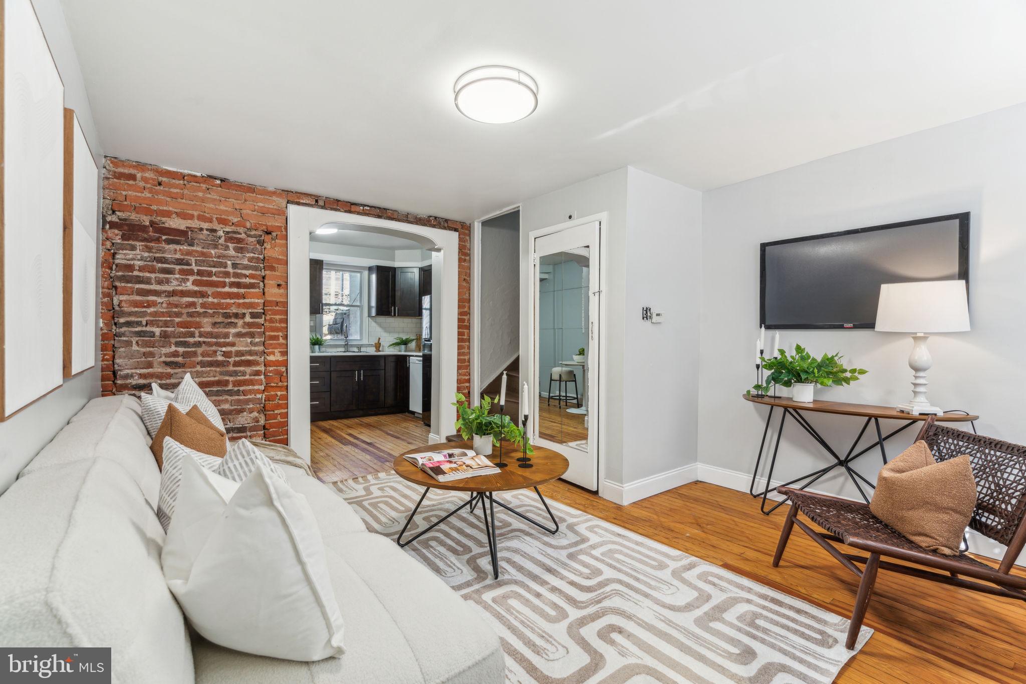 Historic bones meet contemporary updates in this turnkey two-bedroom townhouse featuring an updated kitchen and private patio in coveted Passyunk Square. Inside this 1,033-square-foot home, hardwood floors, exposed brick and a shouldered archway add wonderful warmth and charm alongside fresh paint and updated lighting. A spacious living room with a convenient coat closet flows to the renovated eat-in kitchen featuring custom cabinetry, solid countertops and subway tile backsplashes. Enjoy a full suite of appliances, including a gas range, dishwasher and built-in microwave. The adjacent laundry room with a side-by-side washer-dryer leads to your private rear patio, the perfect setting for summer barbecues and gameday gatherings. A curved staircase leads to the second floor, where you'll find the first bedroom and a bonus office with an en suite windowed bathroom with a glass rain shower and roomy vanity cabinet. The oversized second bedroom encompasses the top floor. The unfinished basement adds abundant storage to this Passyunk Square sanctuary. Located on a tree-lined street inches from East Passyunk Avenue, this fine home is surrounded by some of the best shopping, dining and nightlife South Philly has to offer, including ACME Market and iconic destinations like Geno's, Pat's and the Italian Market. Adjacent playgrounds, parks and dog parks provide fantastic outdoor space, and transportation is effortless with the Tasker Morris SEPTA Station, excellent bus service and freeways all nearby.